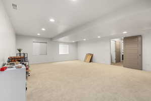 Spacious carpeted room featuring recessed lighting, two windows with horizontal blinds, and a five-panel interior door