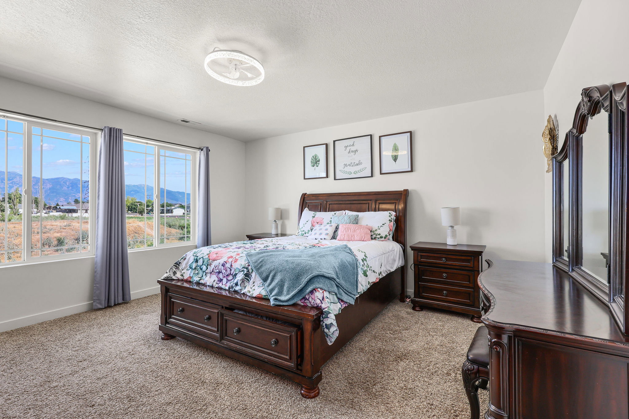 Expansive windows showcasing mountain scenery, complemented by plush carpet flooring, a contemporary ceiling light fixture, and white wall finishes
