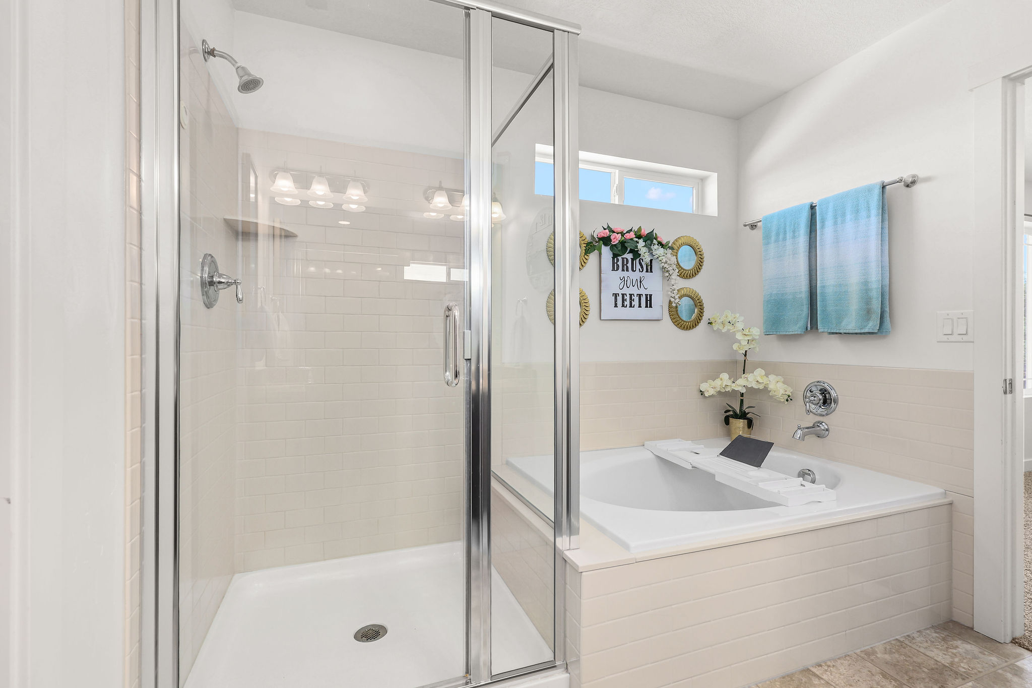 Bathroom featuring a glass-enclosed shower with white subway tile pattern, a built-in tub with tile surround, and a clerestory window