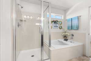 Bathroom featuring a glass-enclosed shower with white subway tile pattern, a built-in tub with tile surround, and a clerestory window