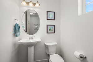 Pedestal sink with chrome faucet, oval mirror, and three-light vanity fixture