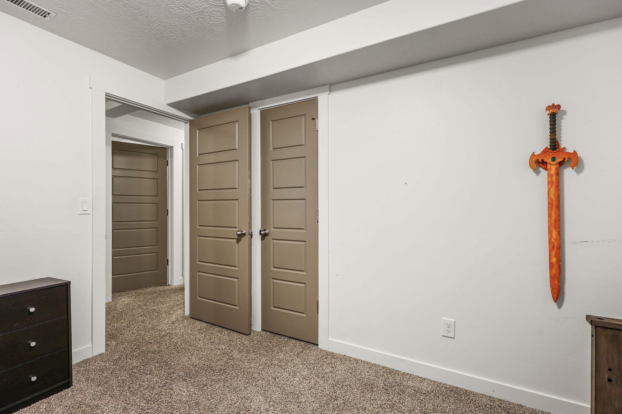 Carpeted room featuring crisp white walls, white trim, and multiple panel doors in a neutral tone