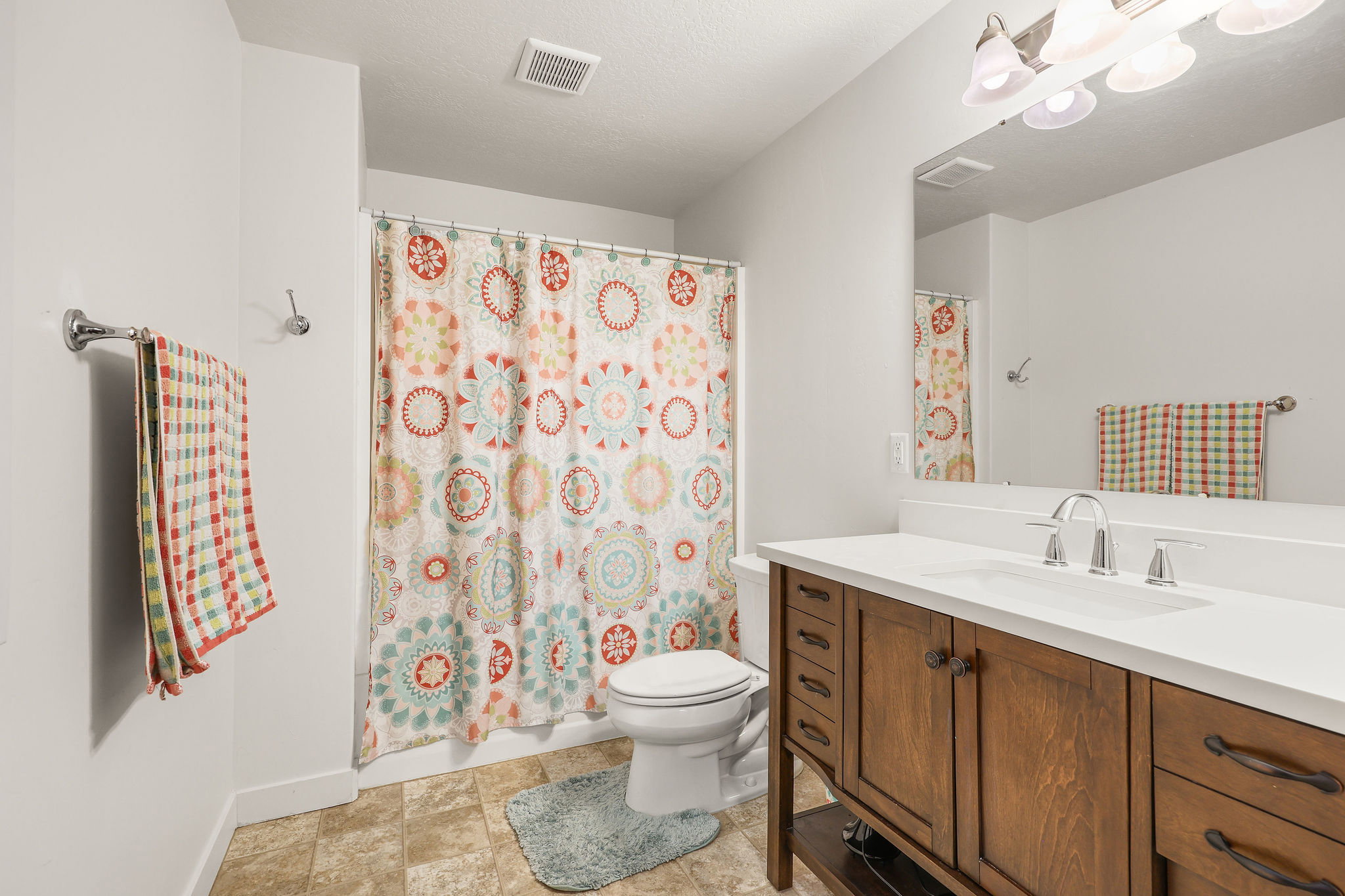 Bathroom featuring a wood-finish vanity with a white countertop, an integrated sink, and a chrome faucet