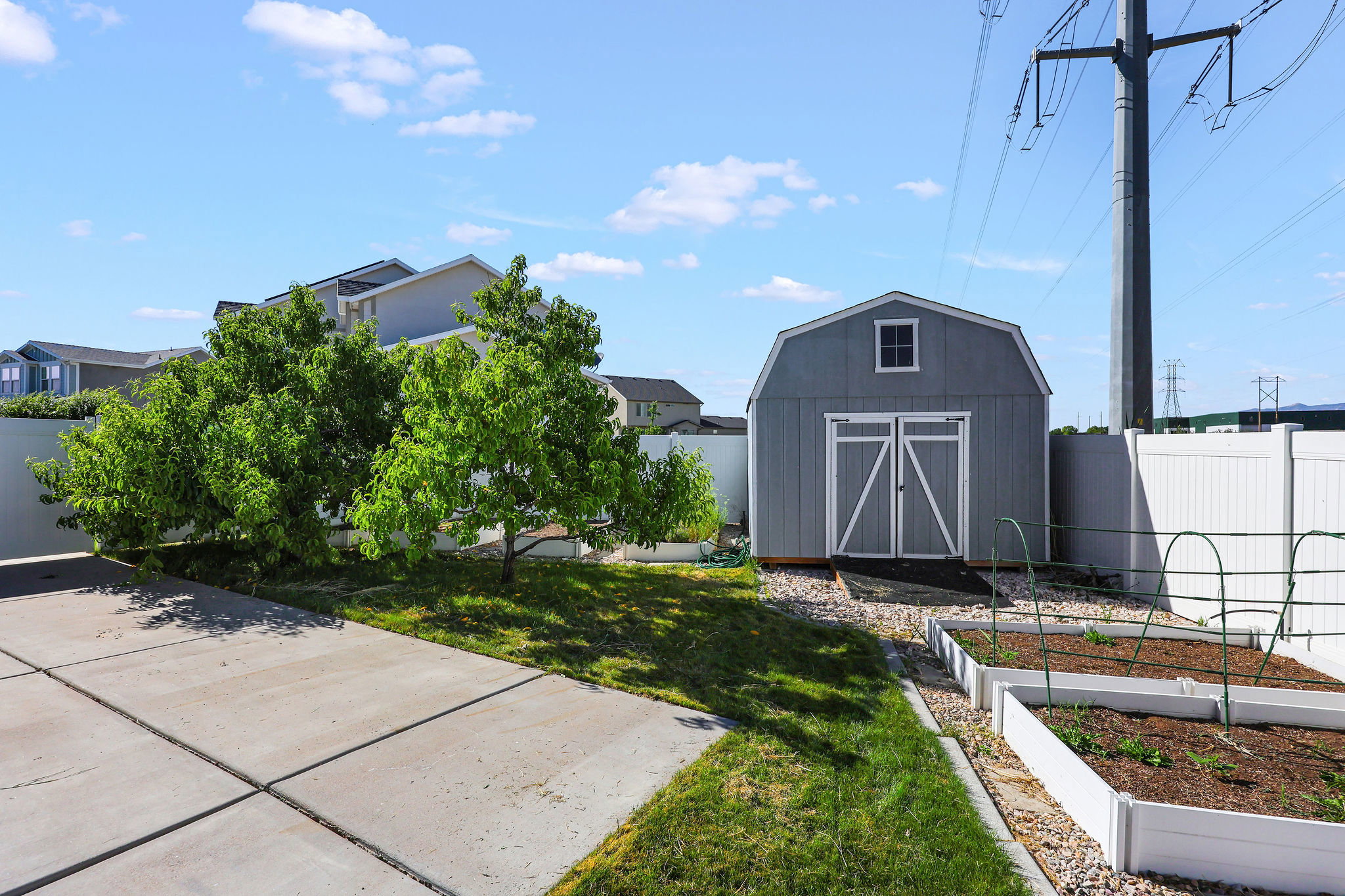 Barn-style storage shed with a small window, gravel landscaping, and raised garden beds