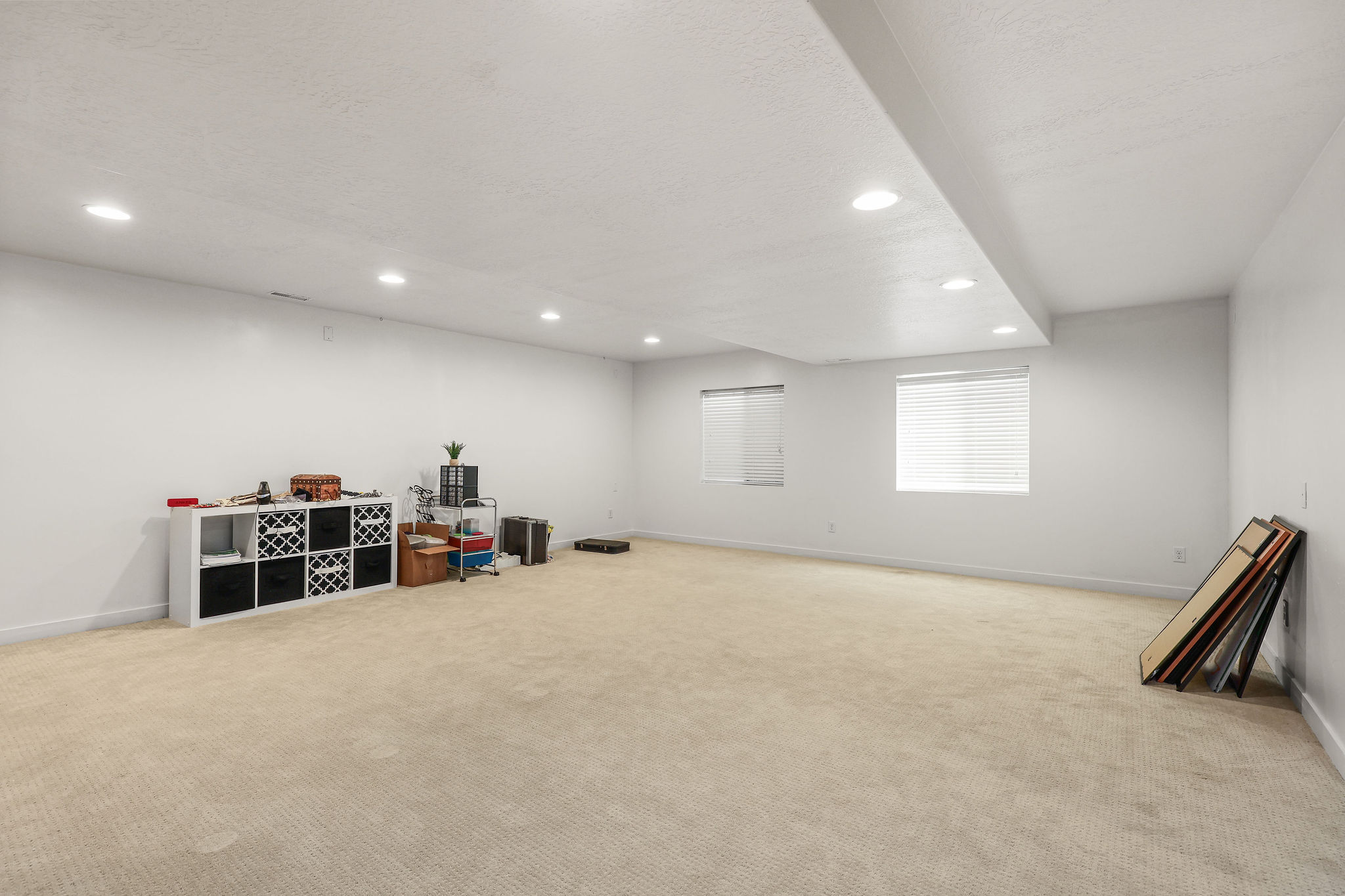 Spacious room featuring neutral carpeting, recessed lighting, white walls, and two windows with blinds