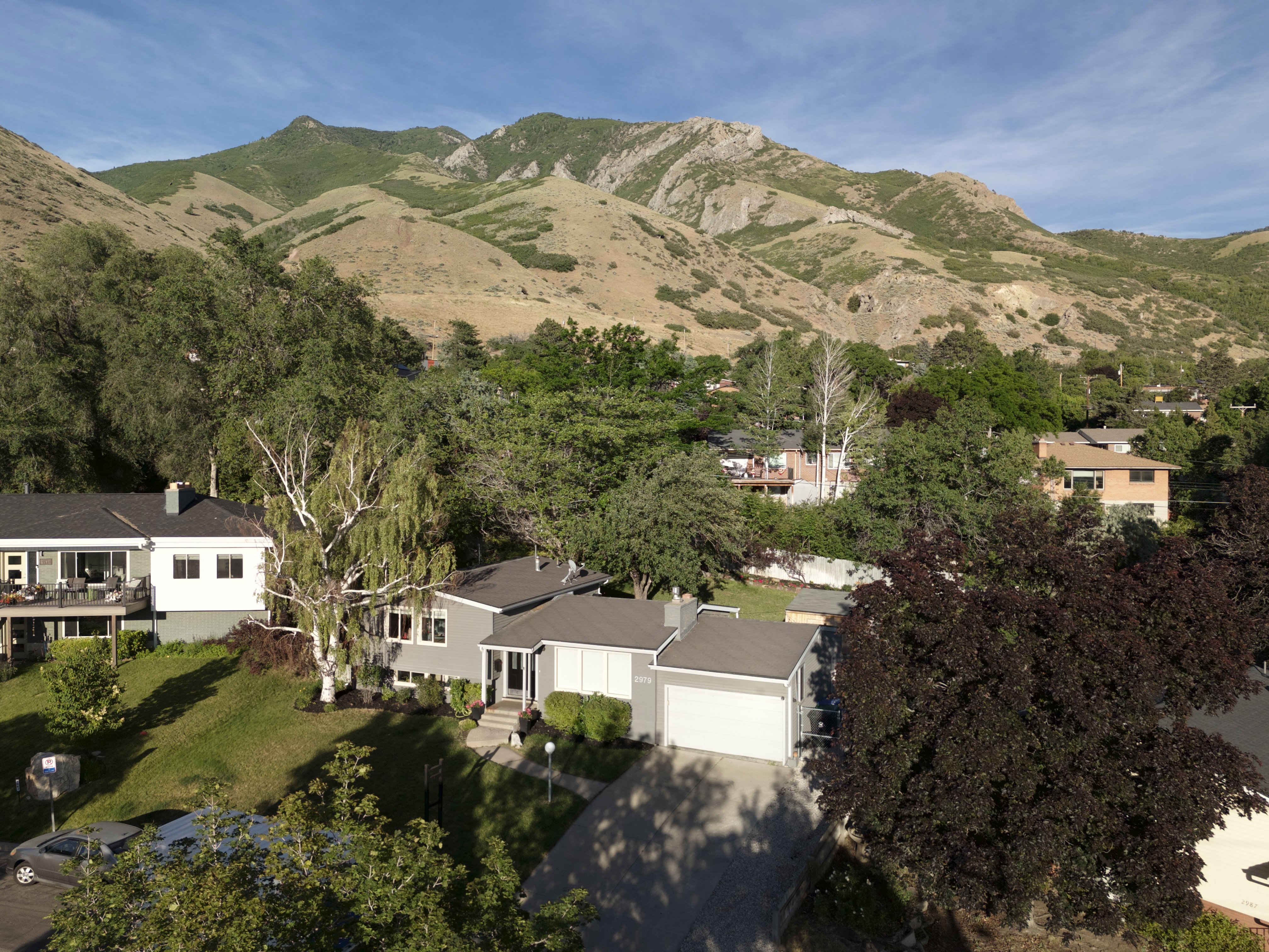 Contemporary residence with a two-car garage, mature trees, and a terraced front lawn