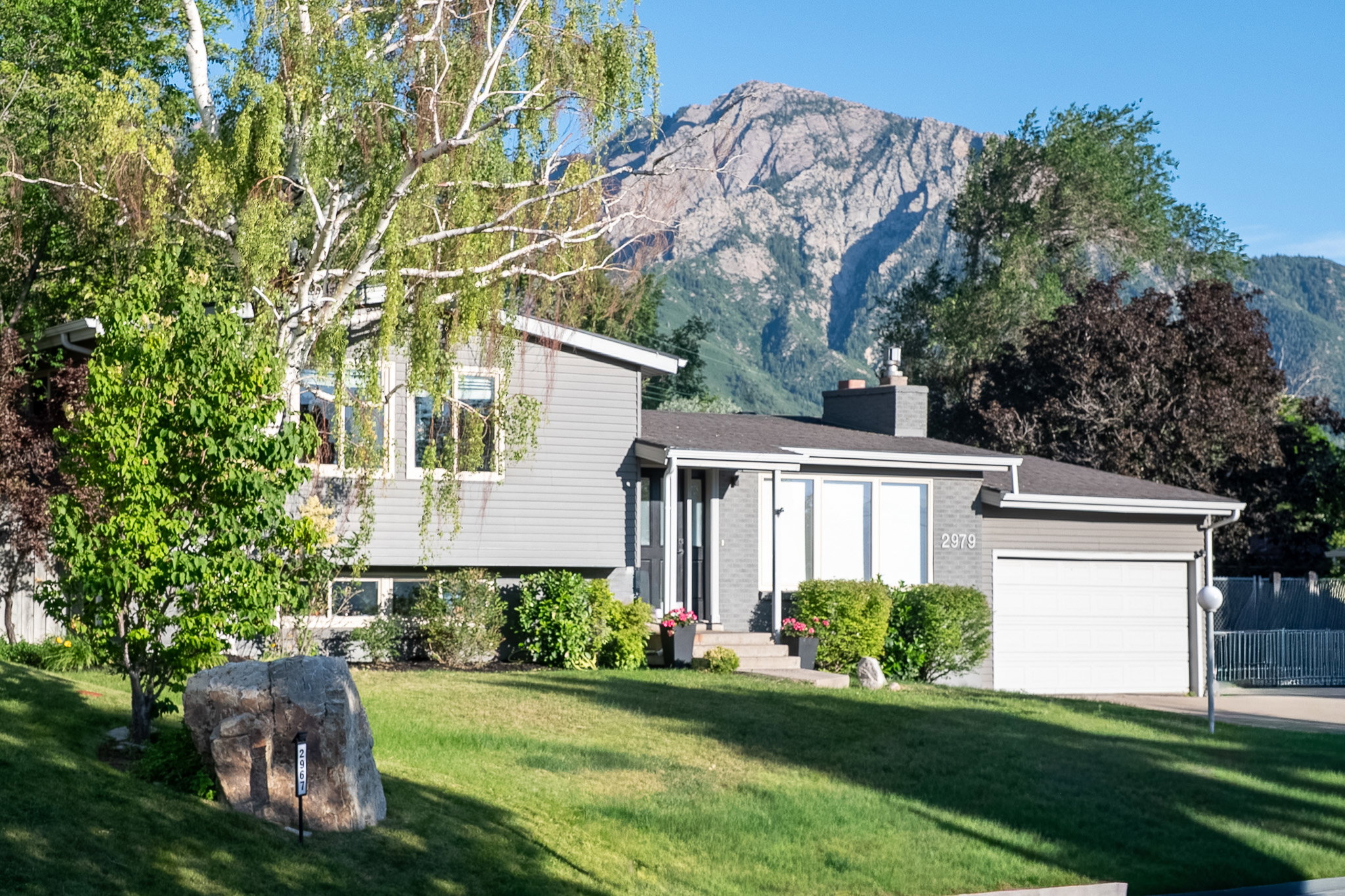 Split-level residence featuring gray siding and a stone facade