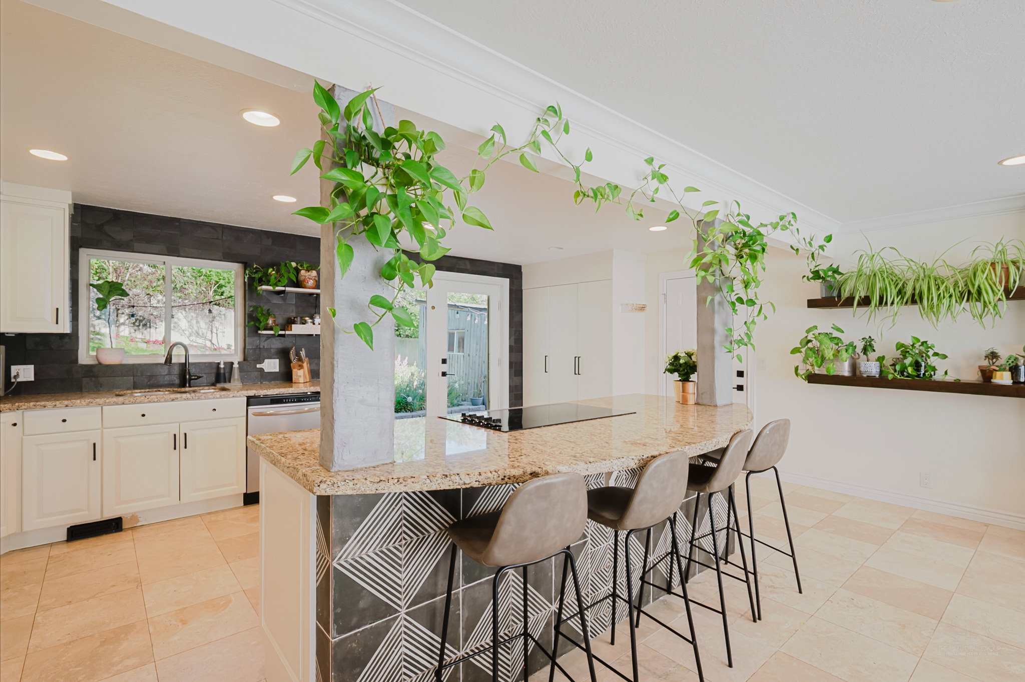 Spacious kitchen with a large central island featuring a granite countertop and geometric tile detailing