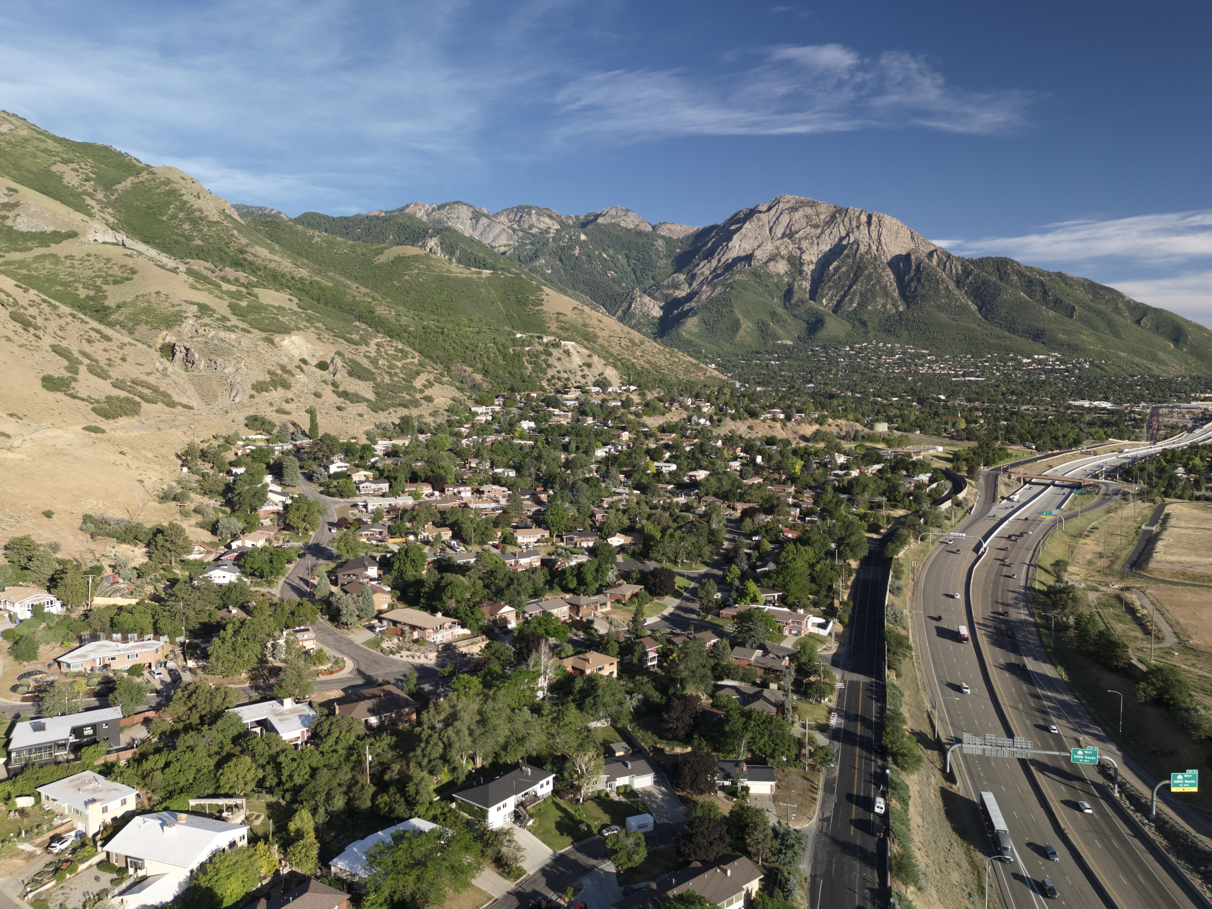 Aerial perspective showcasing a residential community nestled at the base of a verdant mountain range