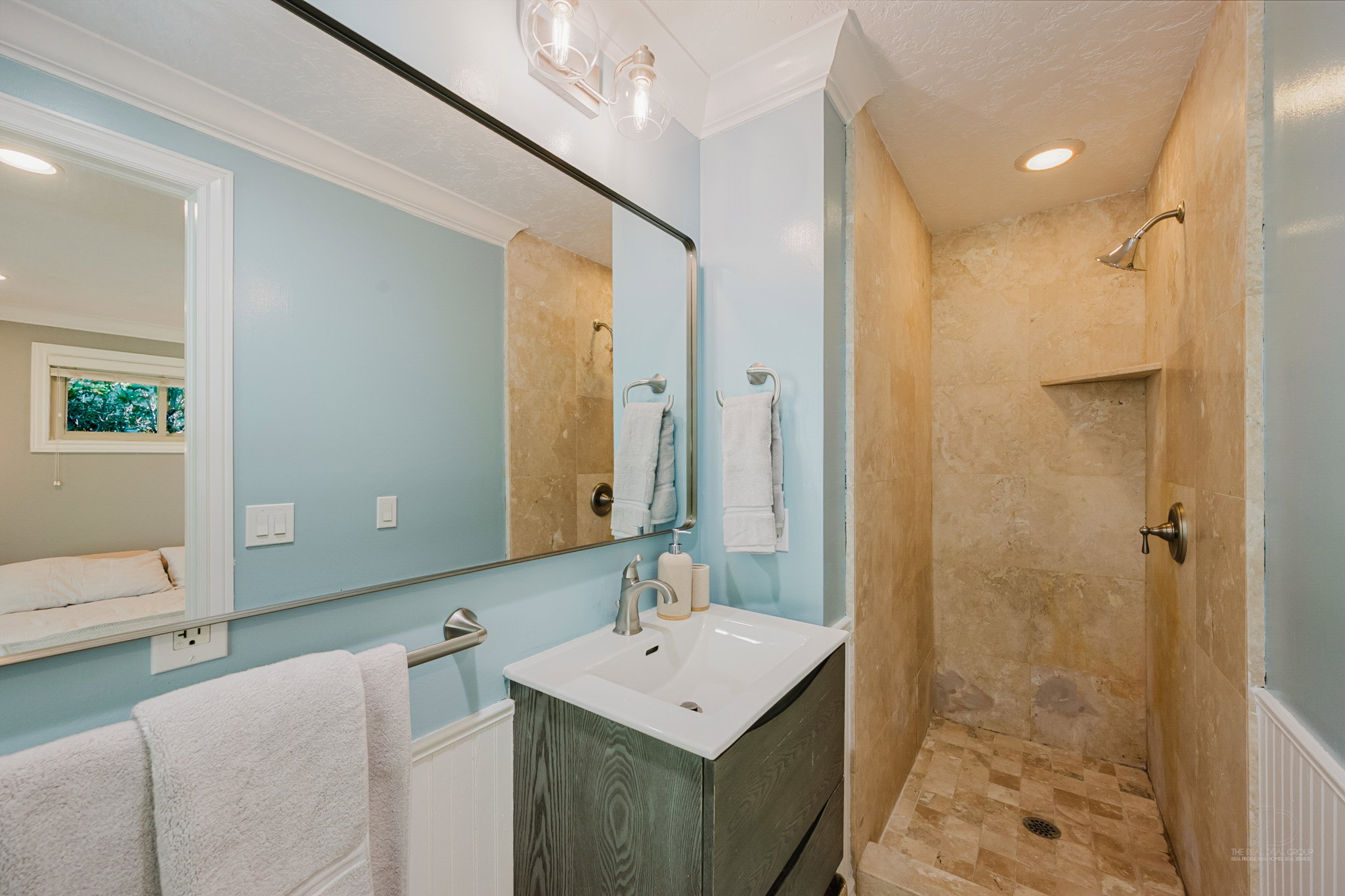 Bathroom featuring a walk-in shower with natural stone-look tiling and a built-in niche