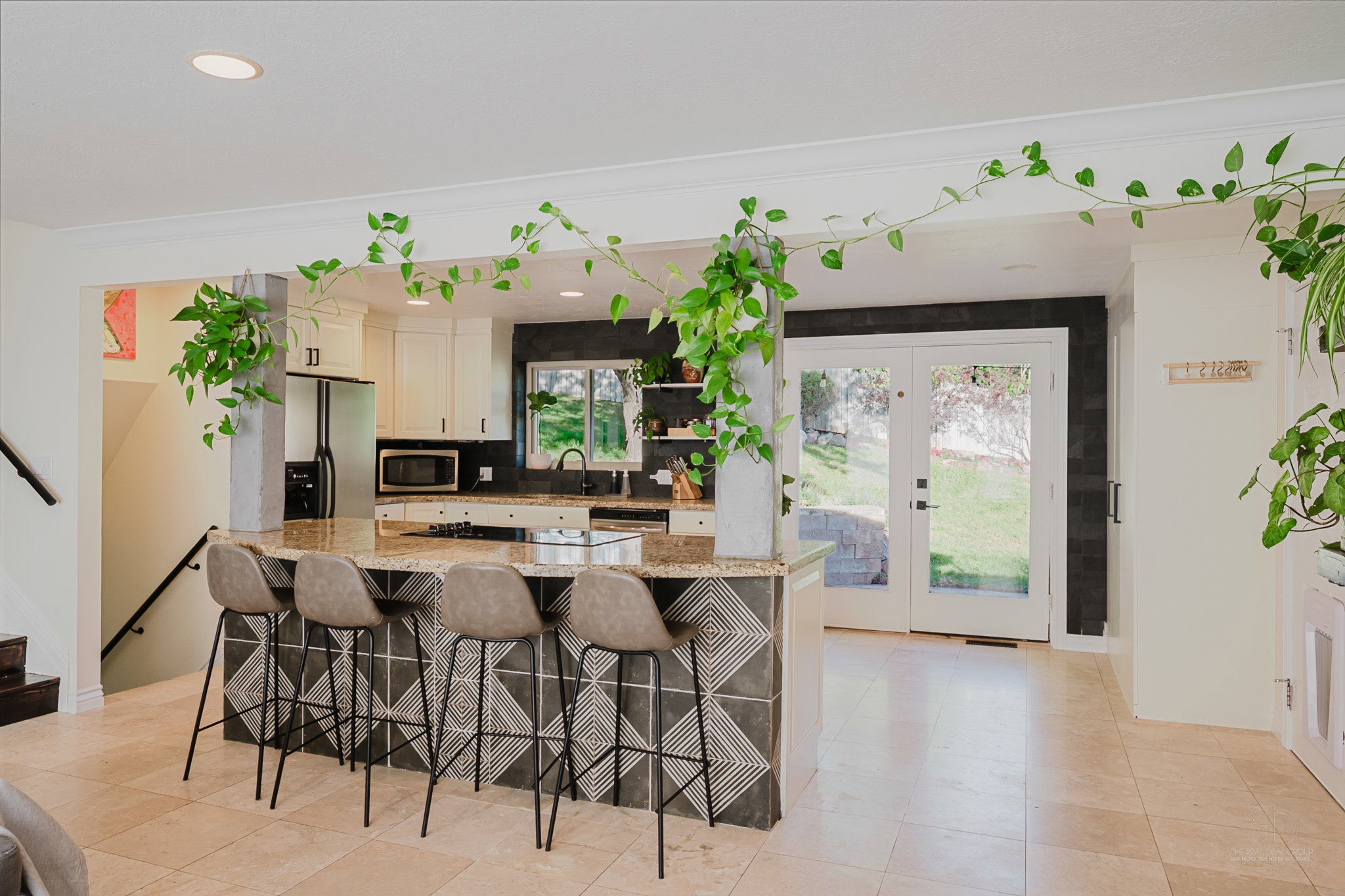 Spacious kitchen featuring an expansive center island with seating, a black subway tile backsplash, white cabinetry, and stainless steel appliances
