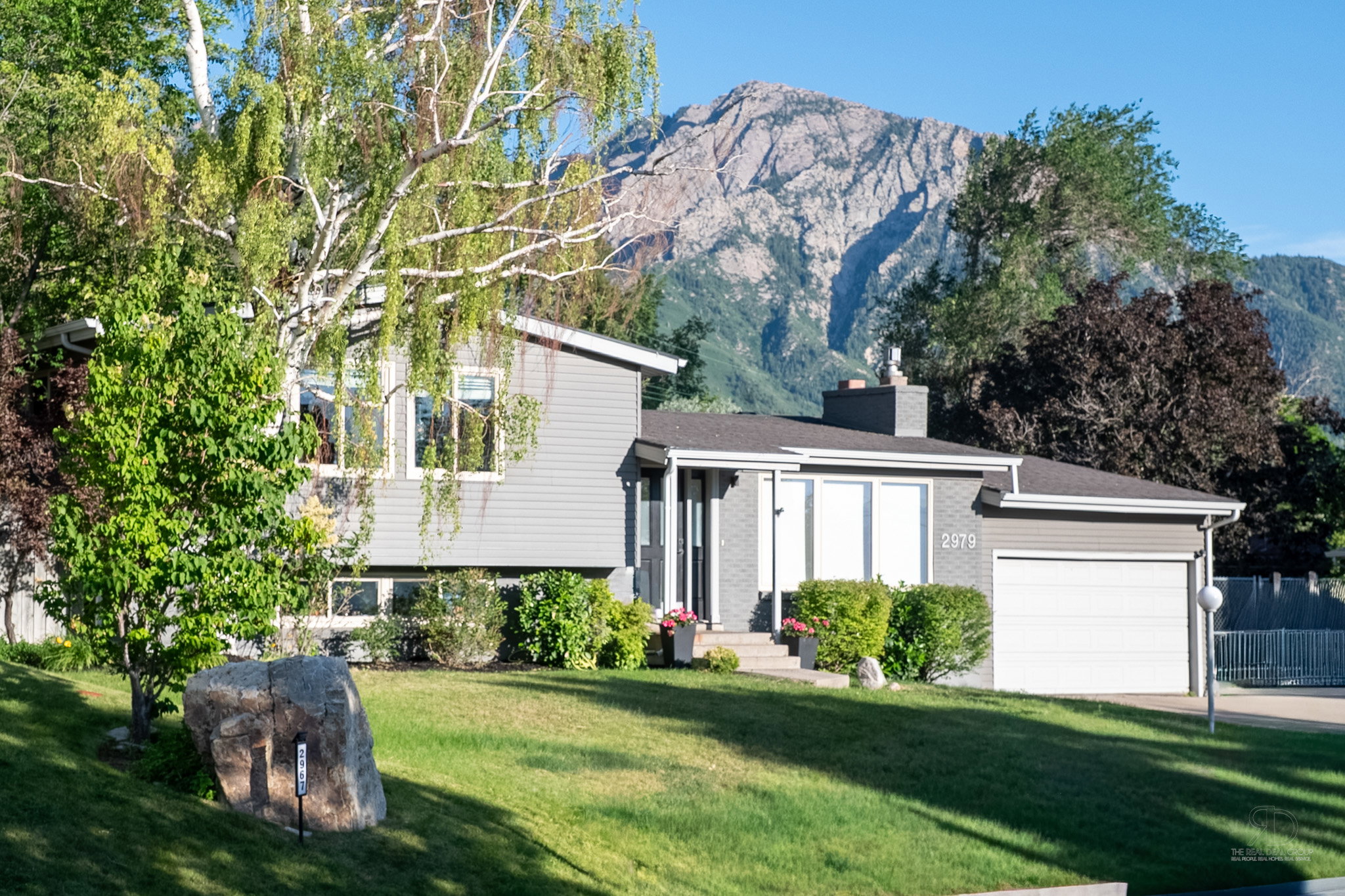 Split-level residence featuring gray siding and a prominent mountain backdrop
