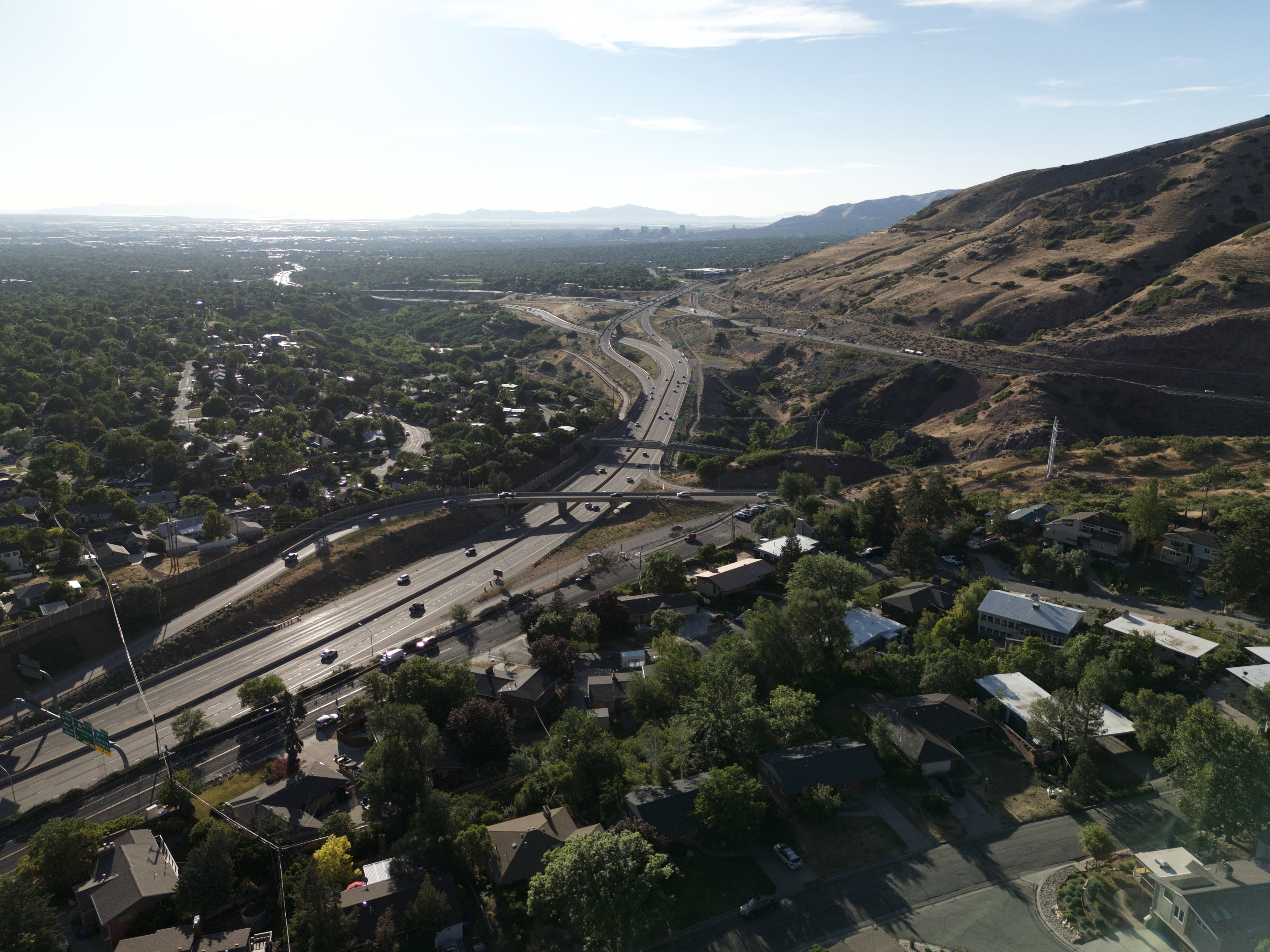 Aerial perspective showcasing a residential area with dense tree cover, a multi-lane highway, and a highway interchange