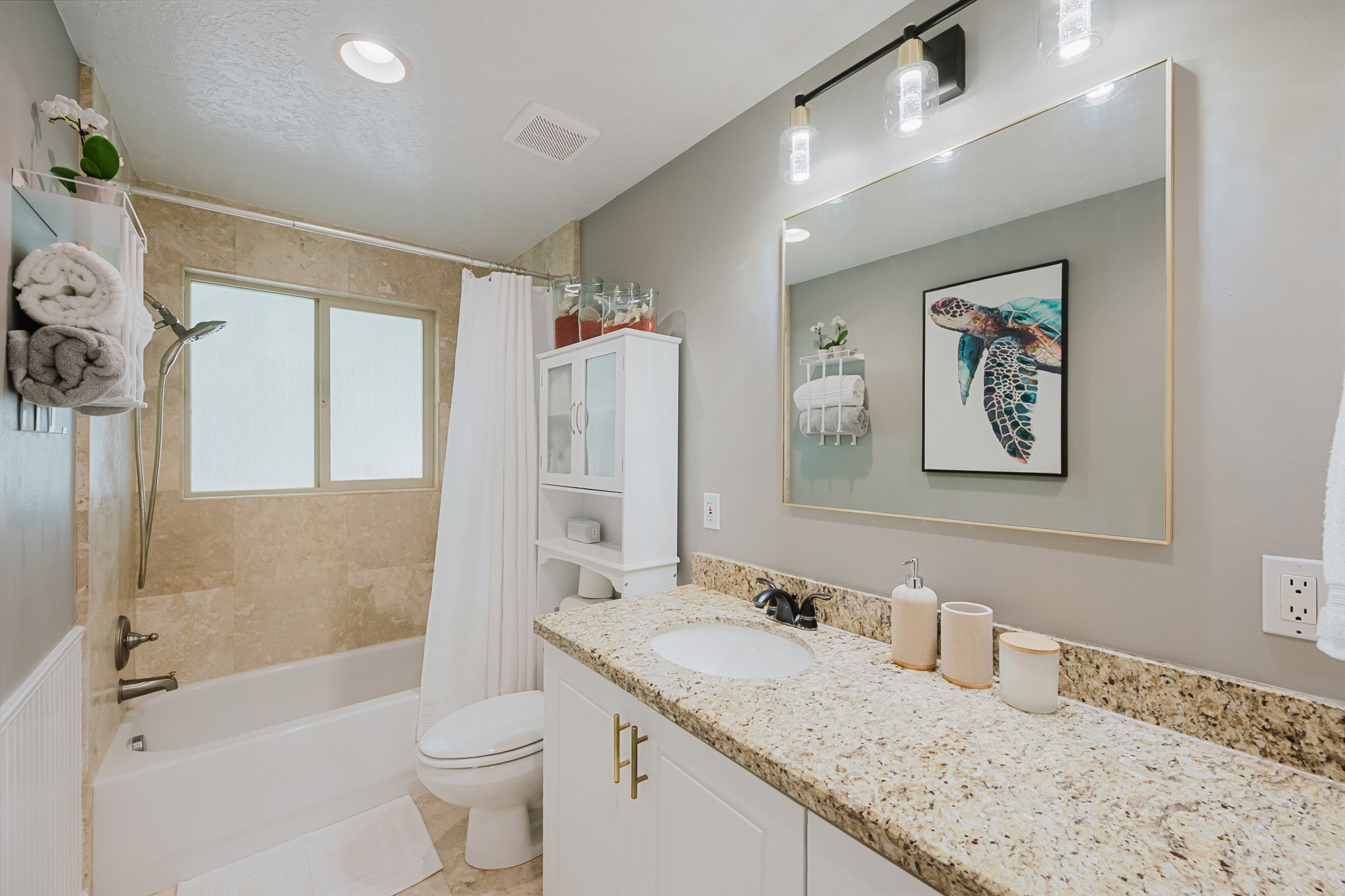 Bathroom featuring a white vanity with gold-tone hardware, a speckled countertop, and a rectangular undermount sink