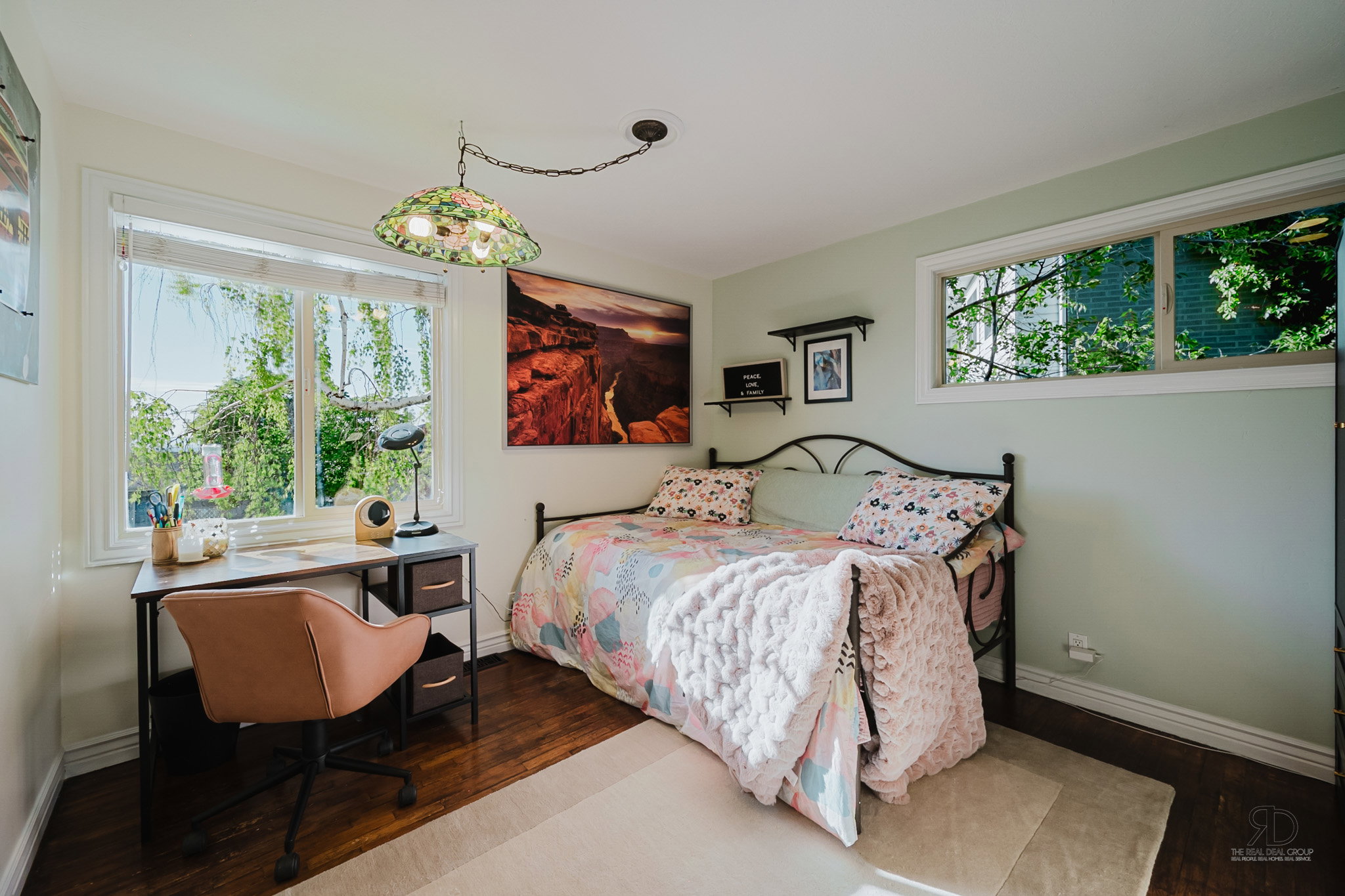 Bright room featuring rich wood-finish flooring and two windows with white trim