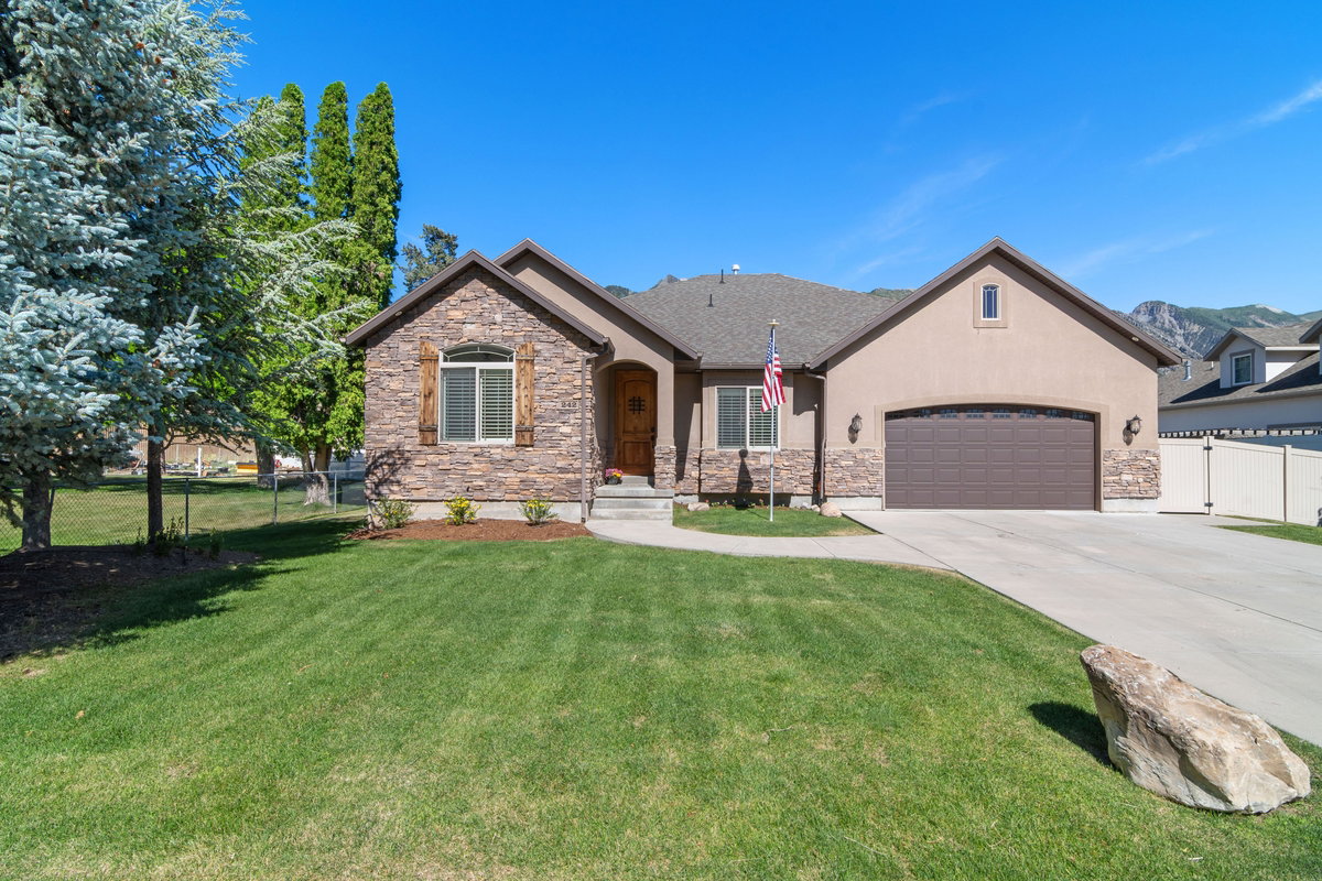 Stone and stucco exterior with a dark asphalt shingle roof