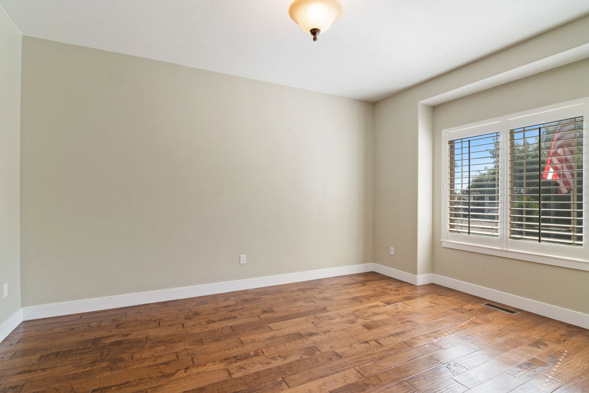 Spacious room featuring wood-finish flooring, light-toned walls, and white trim