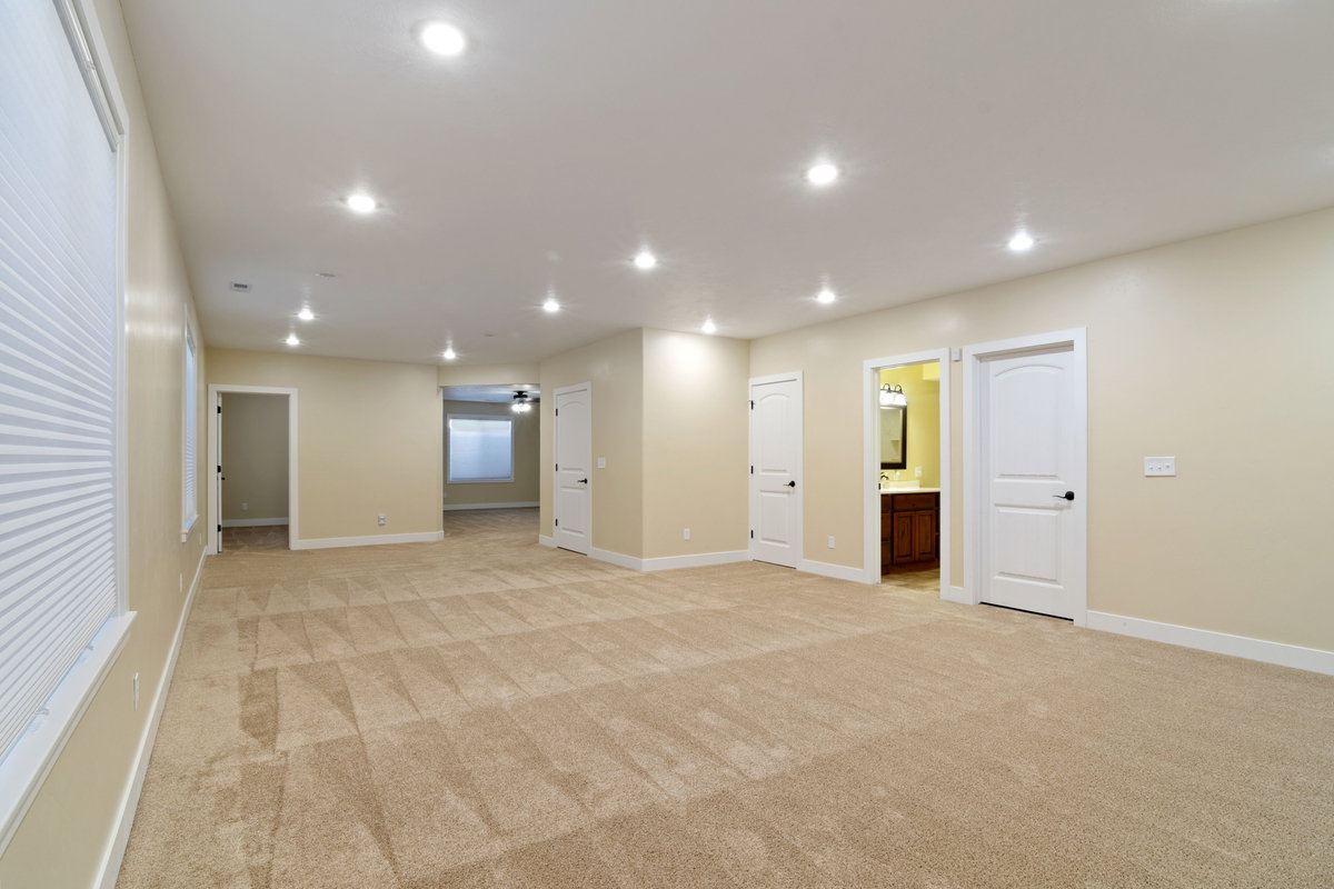 Expansive room featuring recessed lighting, neutral wall tones, and patterned carpeting