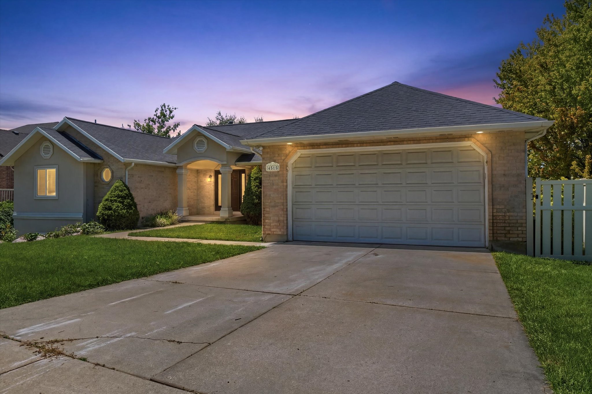 Ranch-style residence featuring a prominent two-car garage, brick veneer accents, a recessed entry, and a gabled roofline