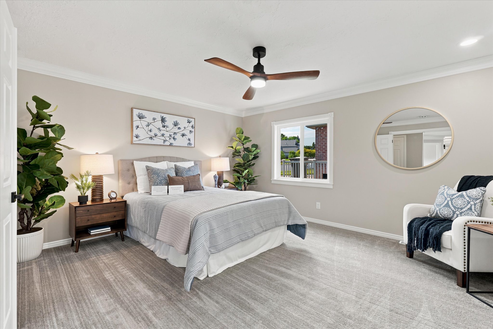 Spacious bedroom featuring plush gray carpeting, crown molding, a ceiling fan with integrated lighting, a large window, and a built-in closet with sliding doors