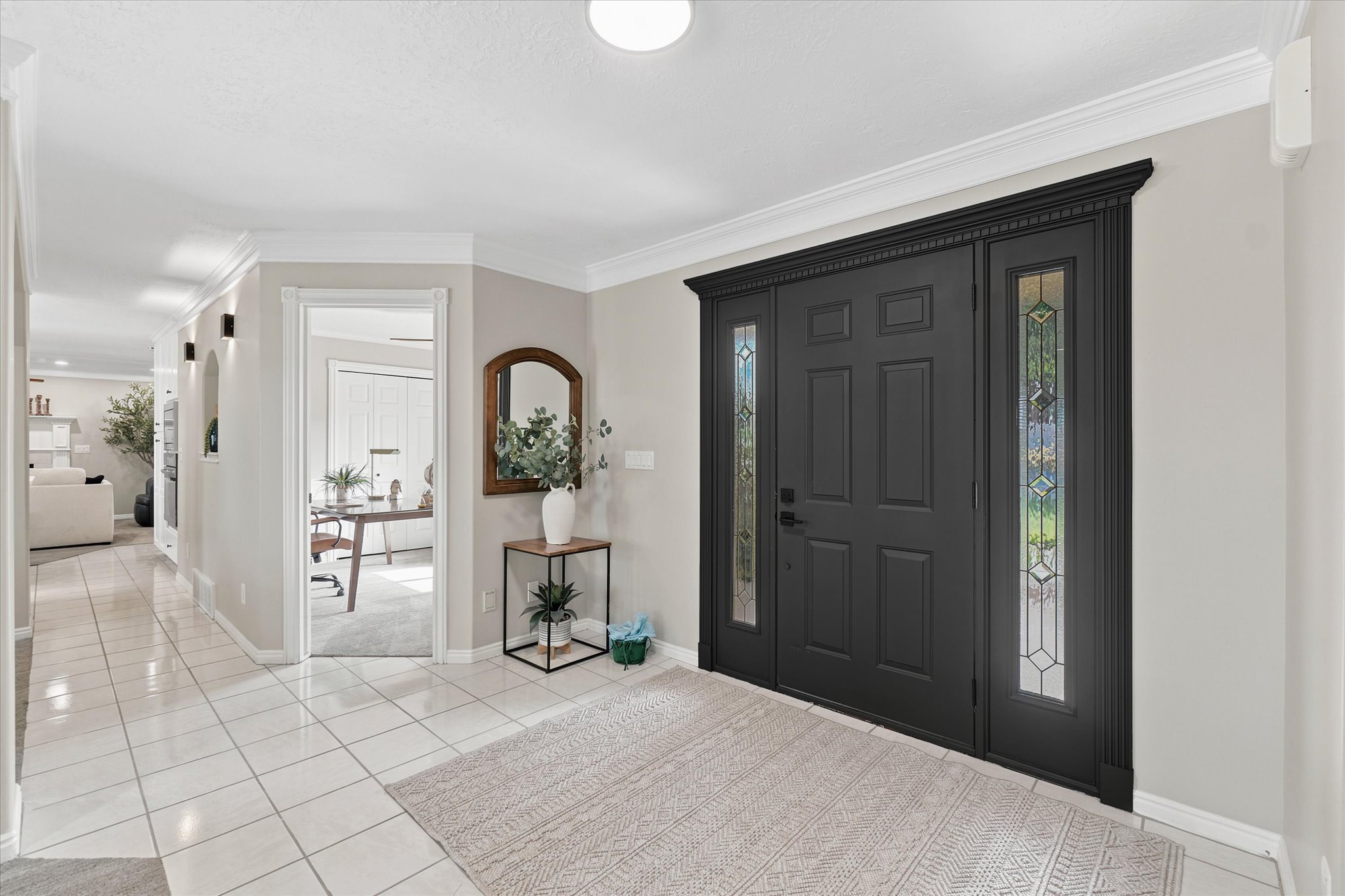 Grand entry with a dark paneled door, decorative glass sidelights, and detailed crown molding