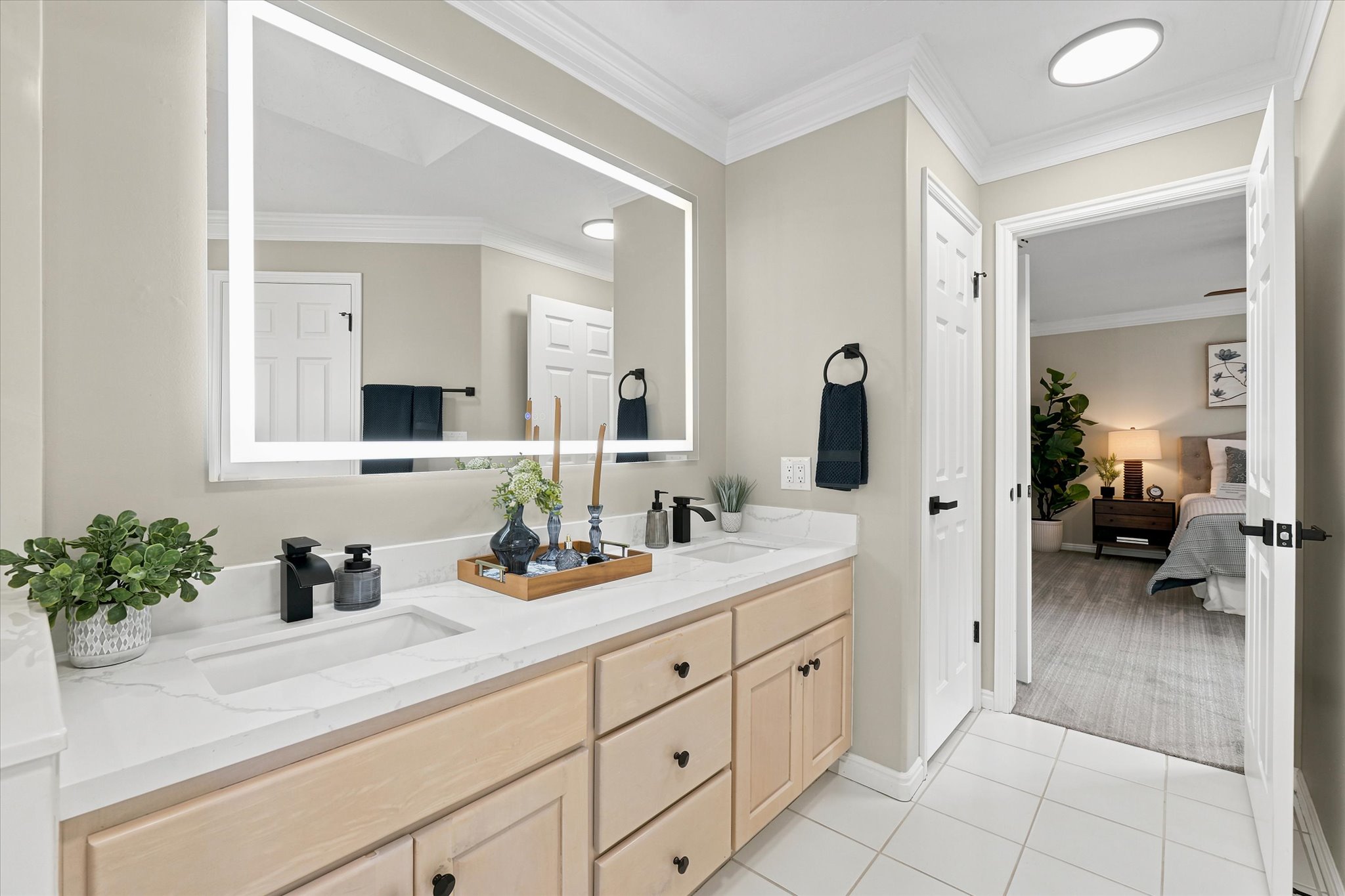 Double vanity featuring integrated sinks, light wood-finish cabinetry, and matte black fixtures