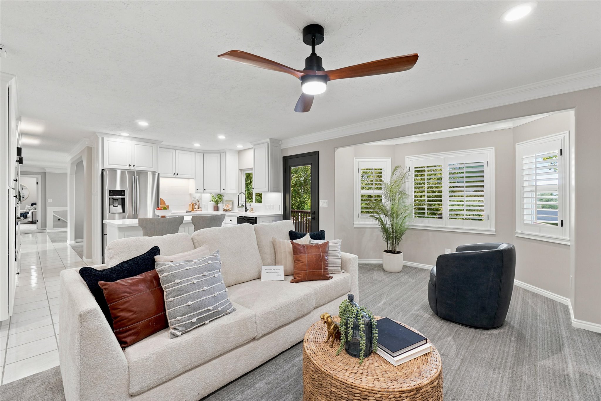 Open-concept living space featuring a ceiling fan with integrated lighting, a bay window with plantation shutters, recessed lighting, and wood-finish flooring