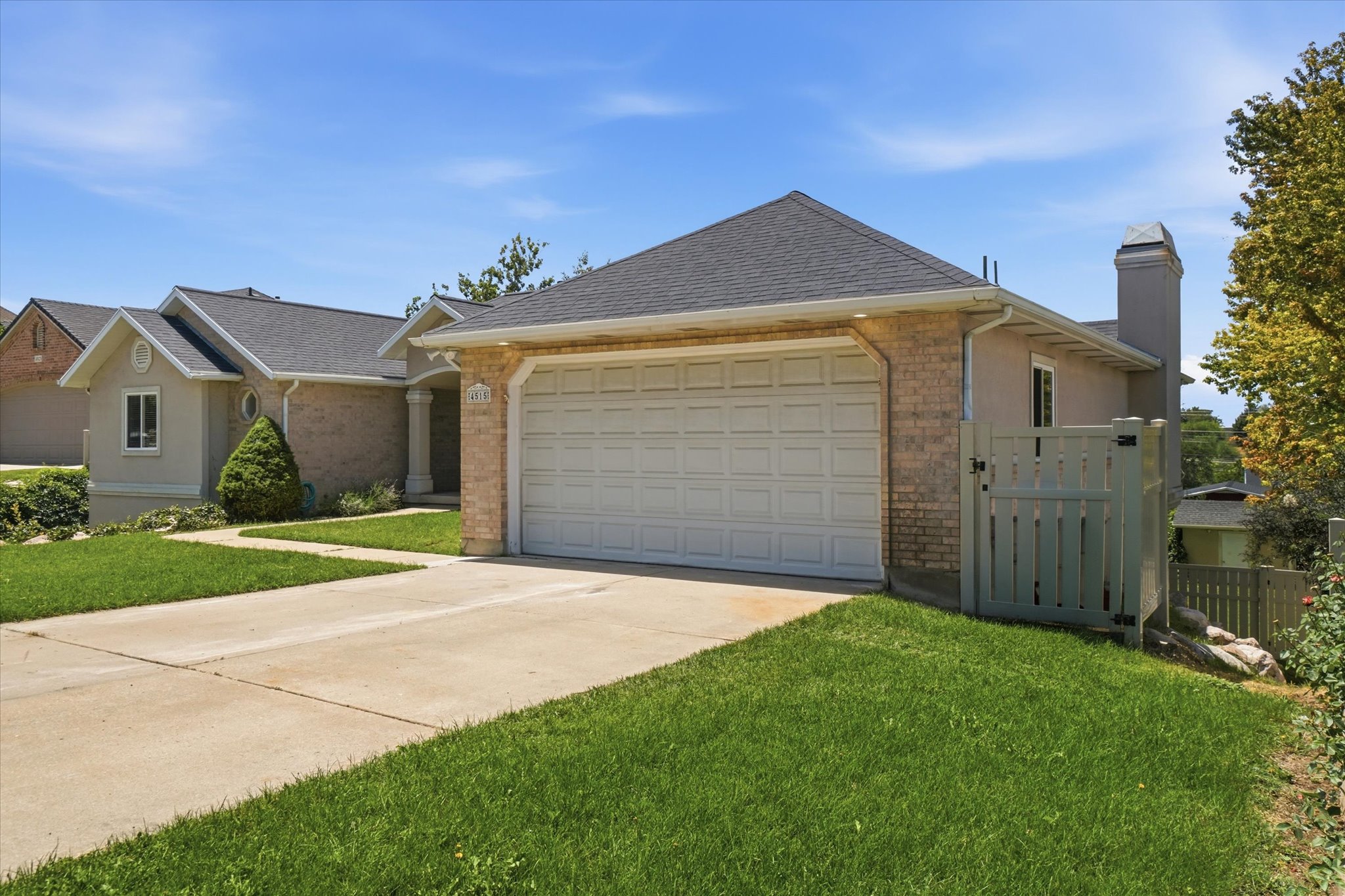 Exterior featuring a concrete driveway, brick facade, attached garage with white door, and a chimney