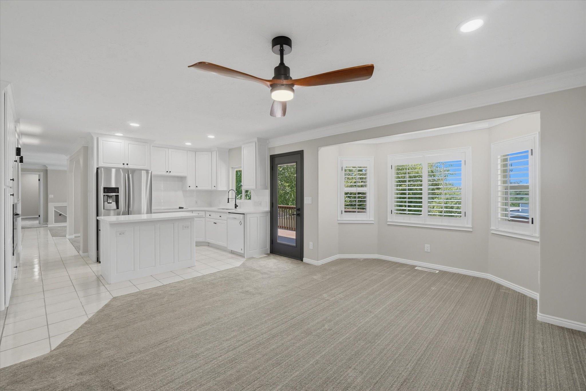 Bright open-concept interior featuring a white kitchen with stainless steel appliances, a center island, and white cabinetry