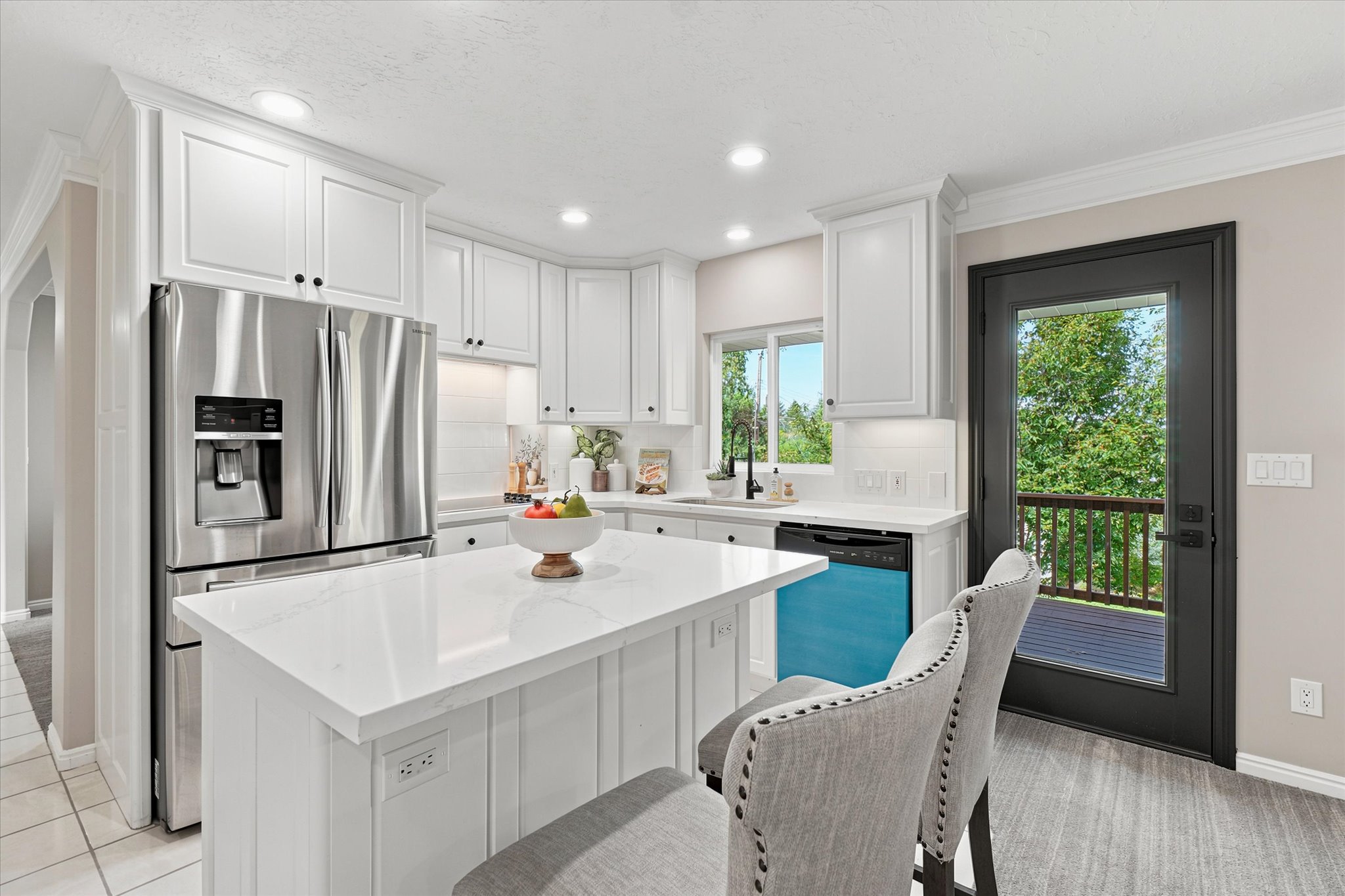 Modern kitchen featuring white cabinetry, a large center island with a quartz-finish countertop, stainless steel appliances, and wood-finish flooring