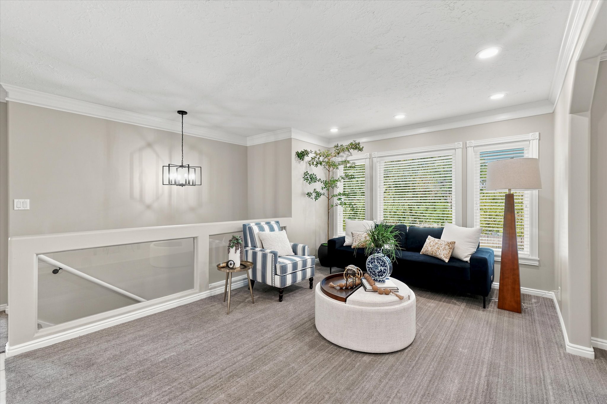 Upper-level lounge area featuring light gray wall paint, recessed lighting, and crown molding
