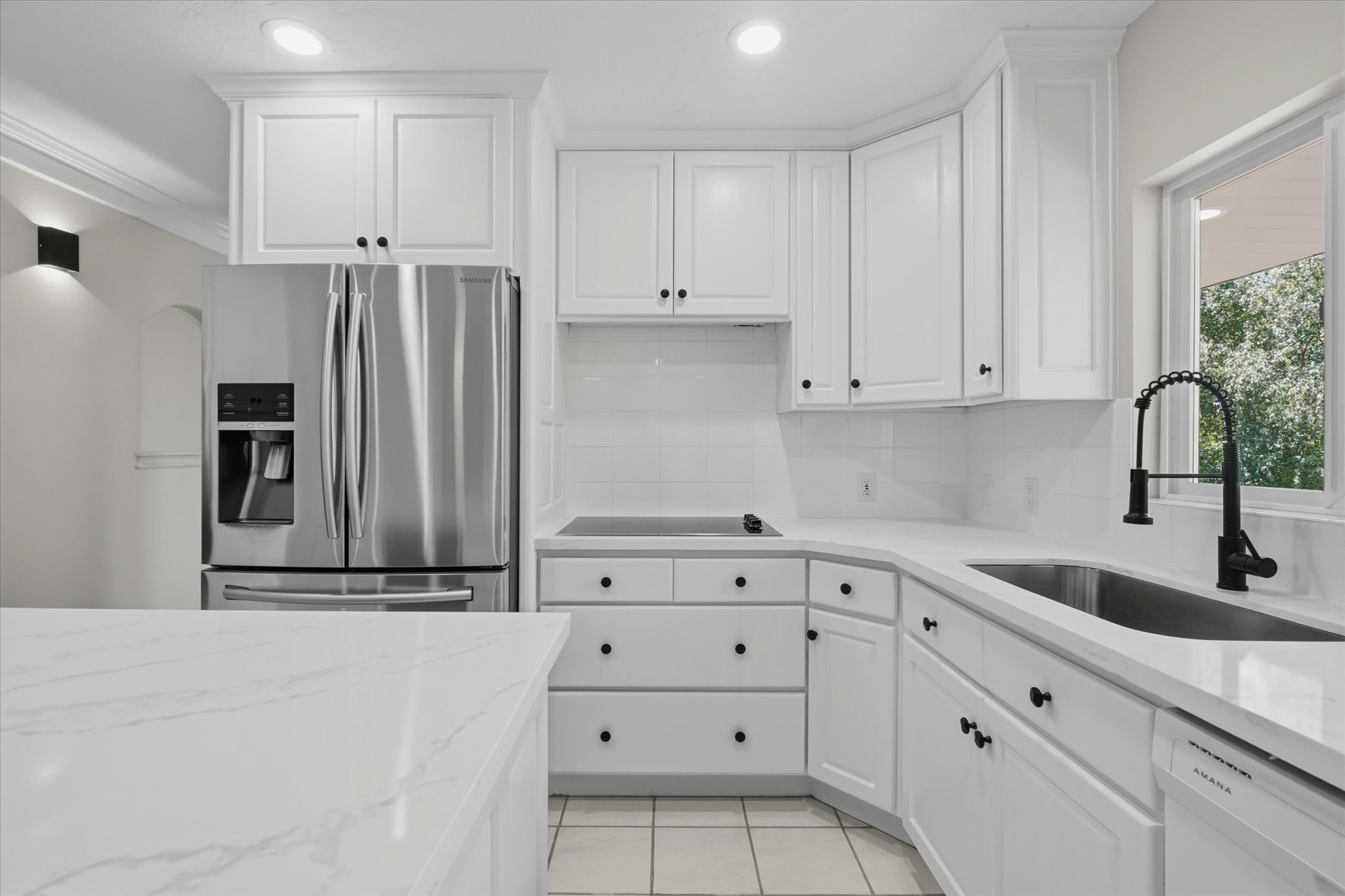 Bright kitchen featuring white shaker cabinetry, stainless steel appliances, white countertops, and a subway tile backsplash