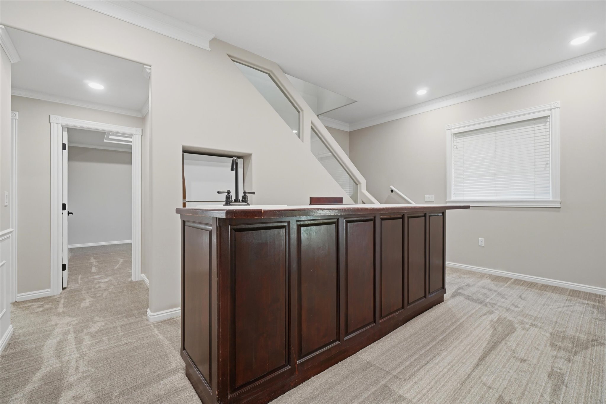 Built-in wet bar featuring dark wood cabinetry, a light-toned countertop, and a matte black faucet