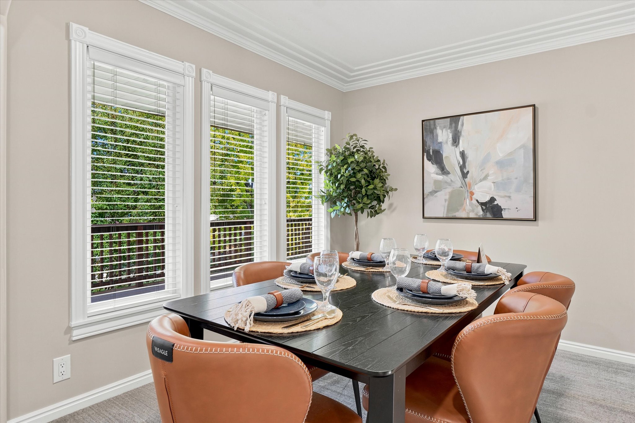 Dining area featuring a dark wood-finish table, multiple paneled windows with white blinds, crown molding, and light gray wall paint