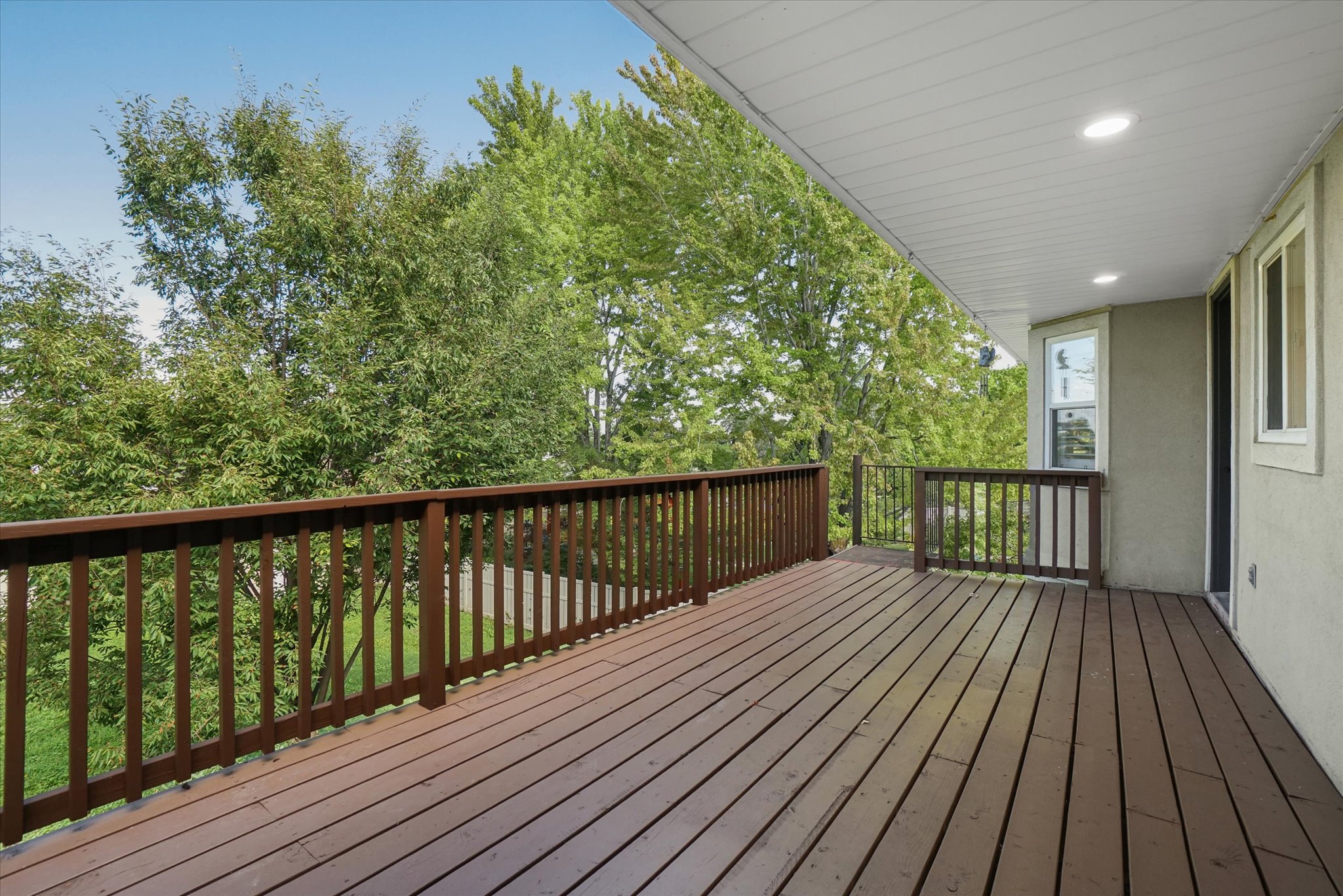 Spacious outdoor deck featuring wood-finish decking and dark wood railings