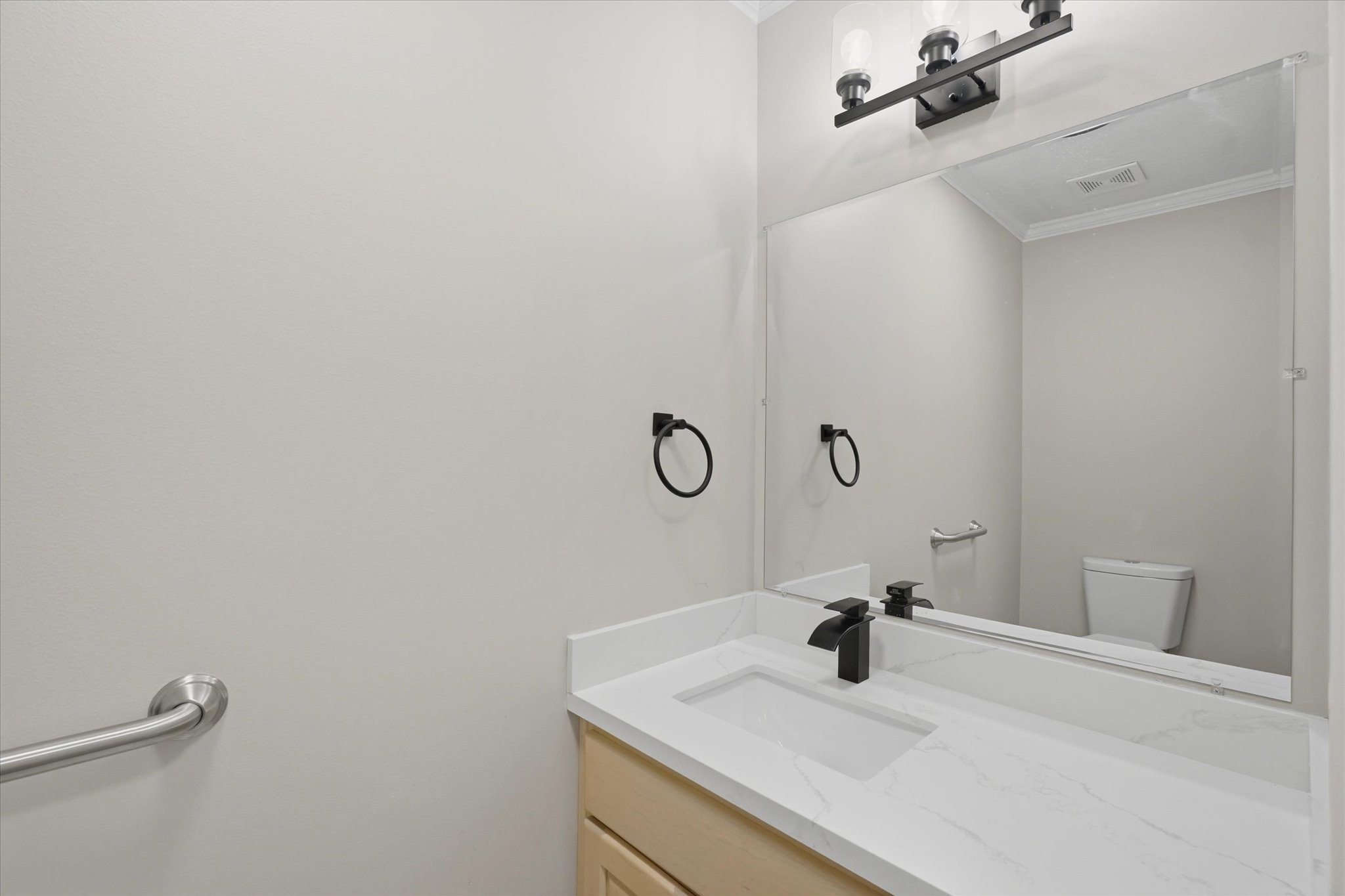 Bathroom vanity featuring a quartz countertop with an integrated rectangular sink, a matte black single-handle faucet, and a large wall-mounted mirror