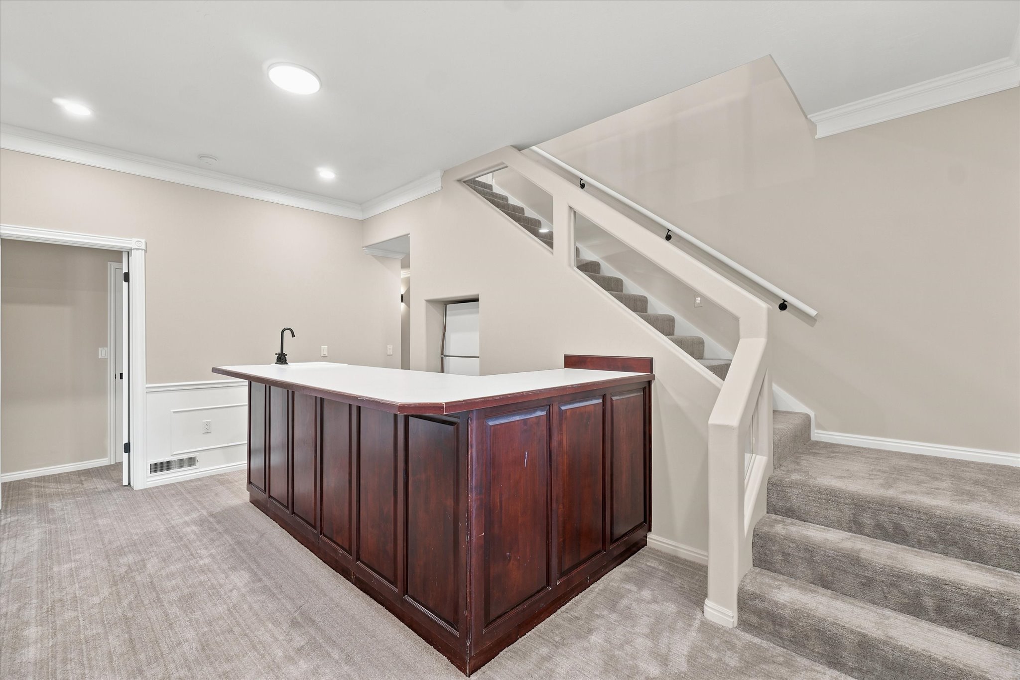 Custom built-in bar with white countertop and integrated sink with matte black faucet