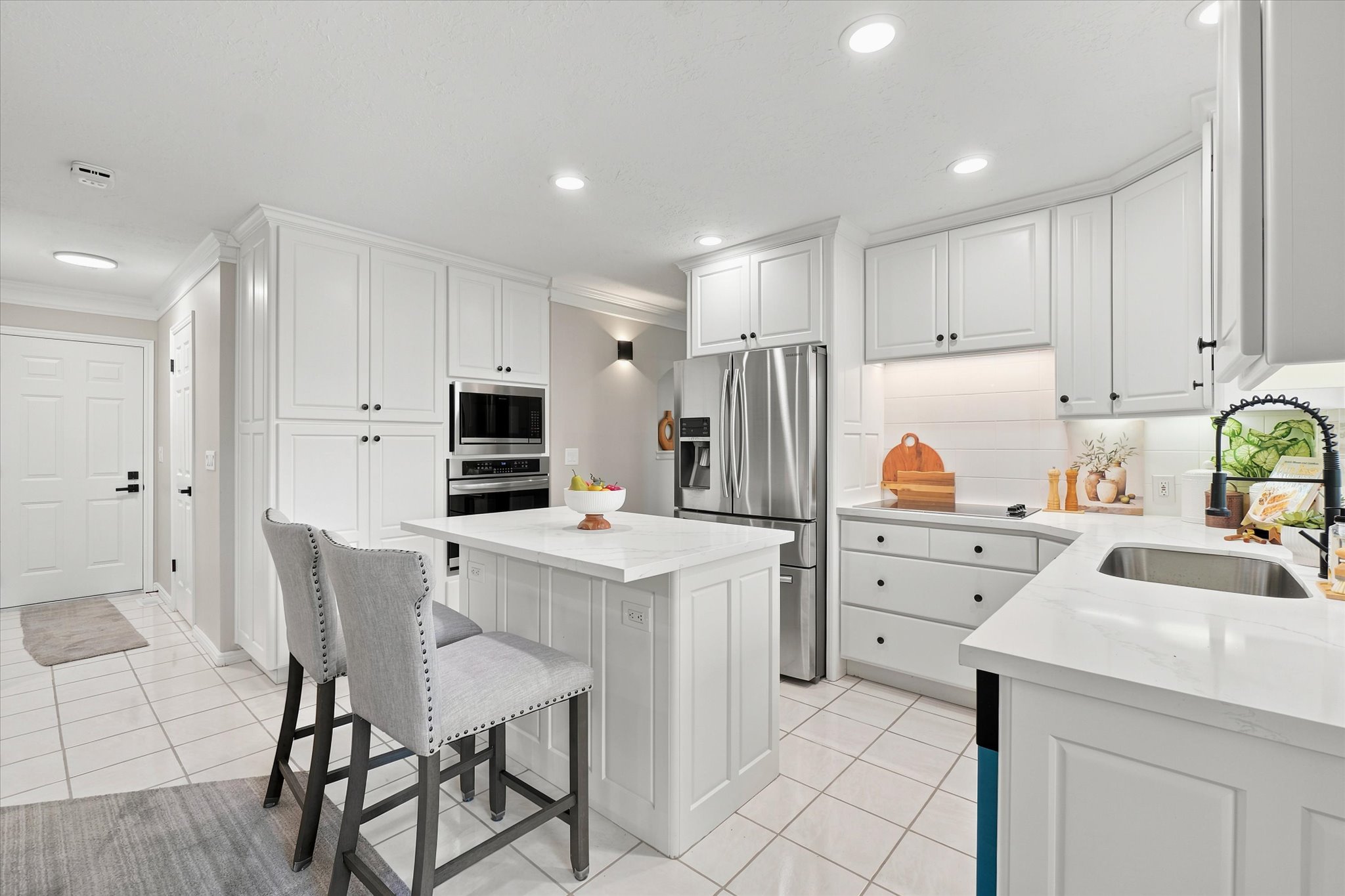 Modern kitchen featuring white shaker cabinetry with black hardware, stainless steel appliances, and an undermount sink