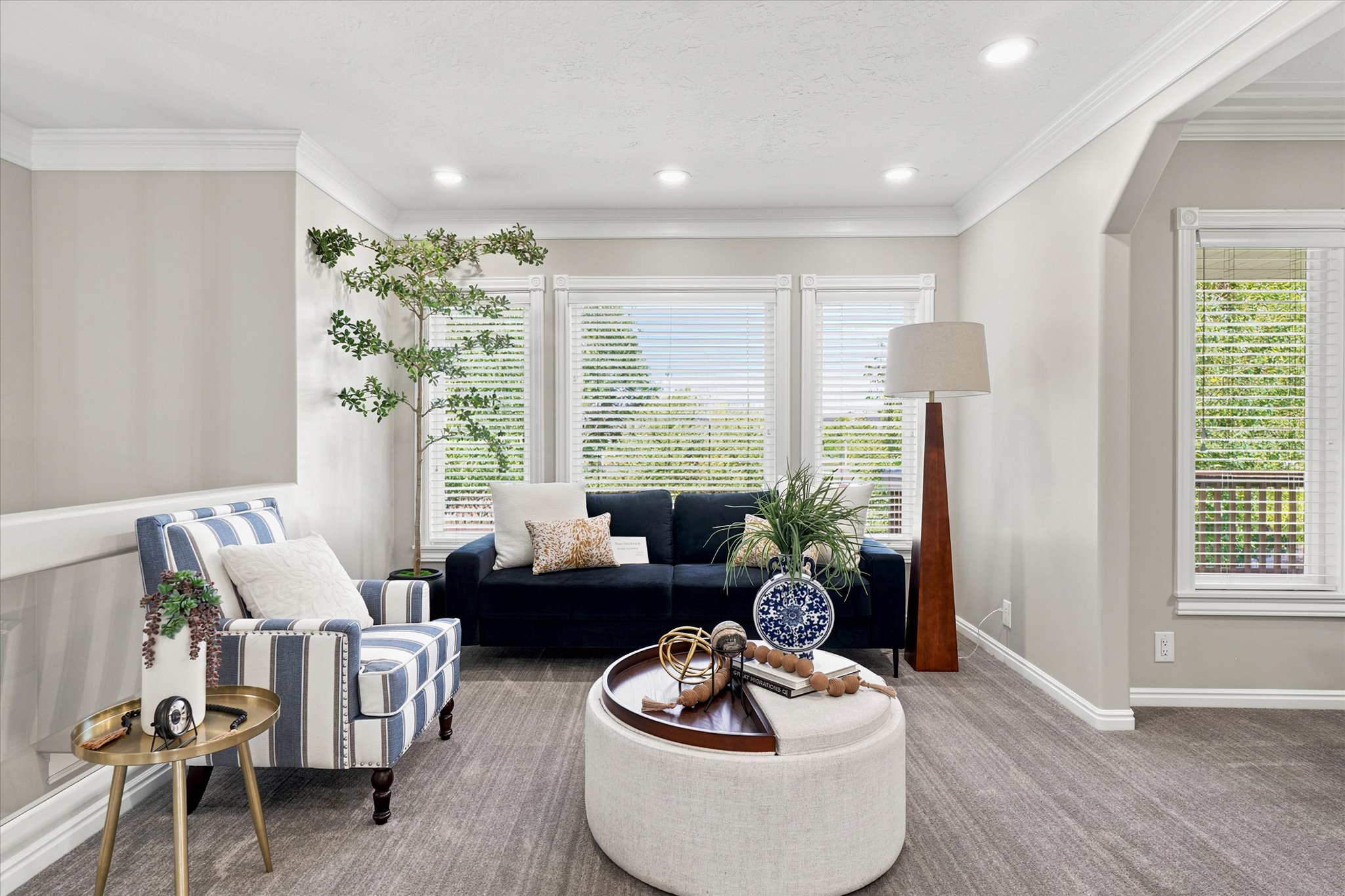 Living area featuring a triple window arrangement, crown molding, recessed lighting, carpet flooring, and a cased opening