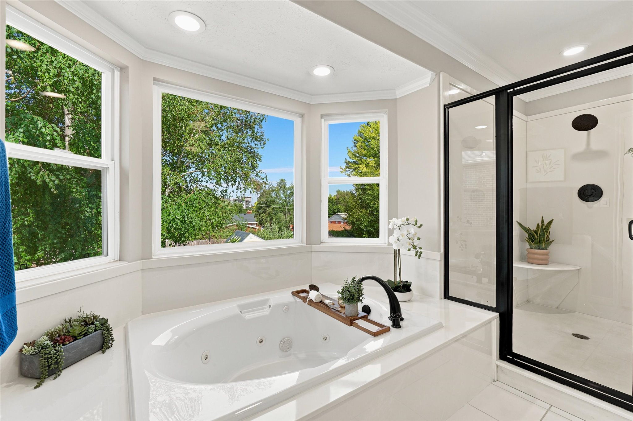 Bathroom featuring a built-in jetted tub, expansive window array, and an enclosed shower