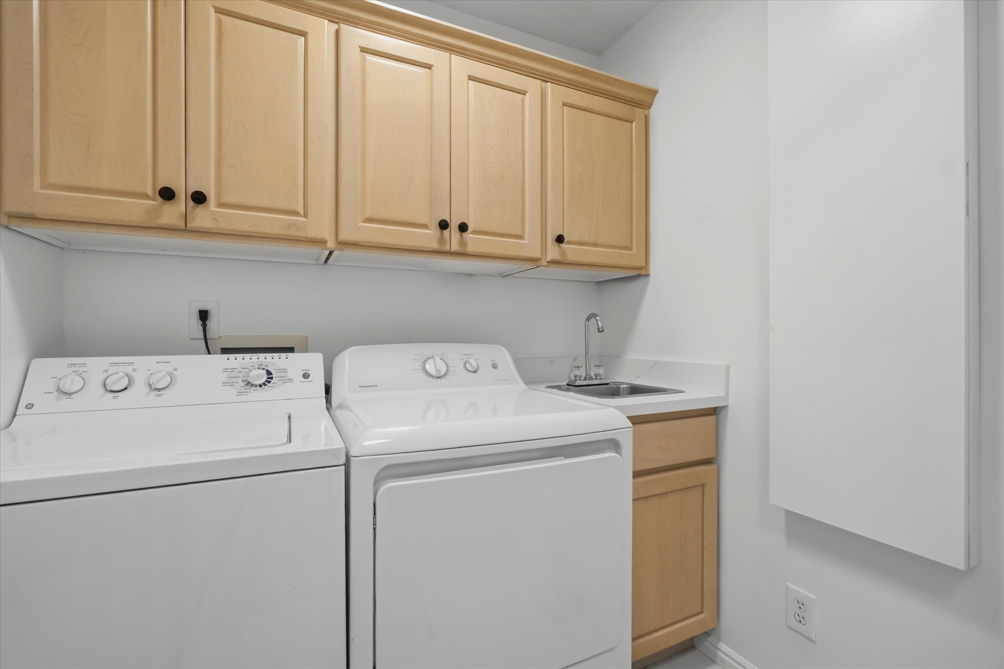 Dedicated laundry area featuring upper and lower cabinetry, and a utility sink