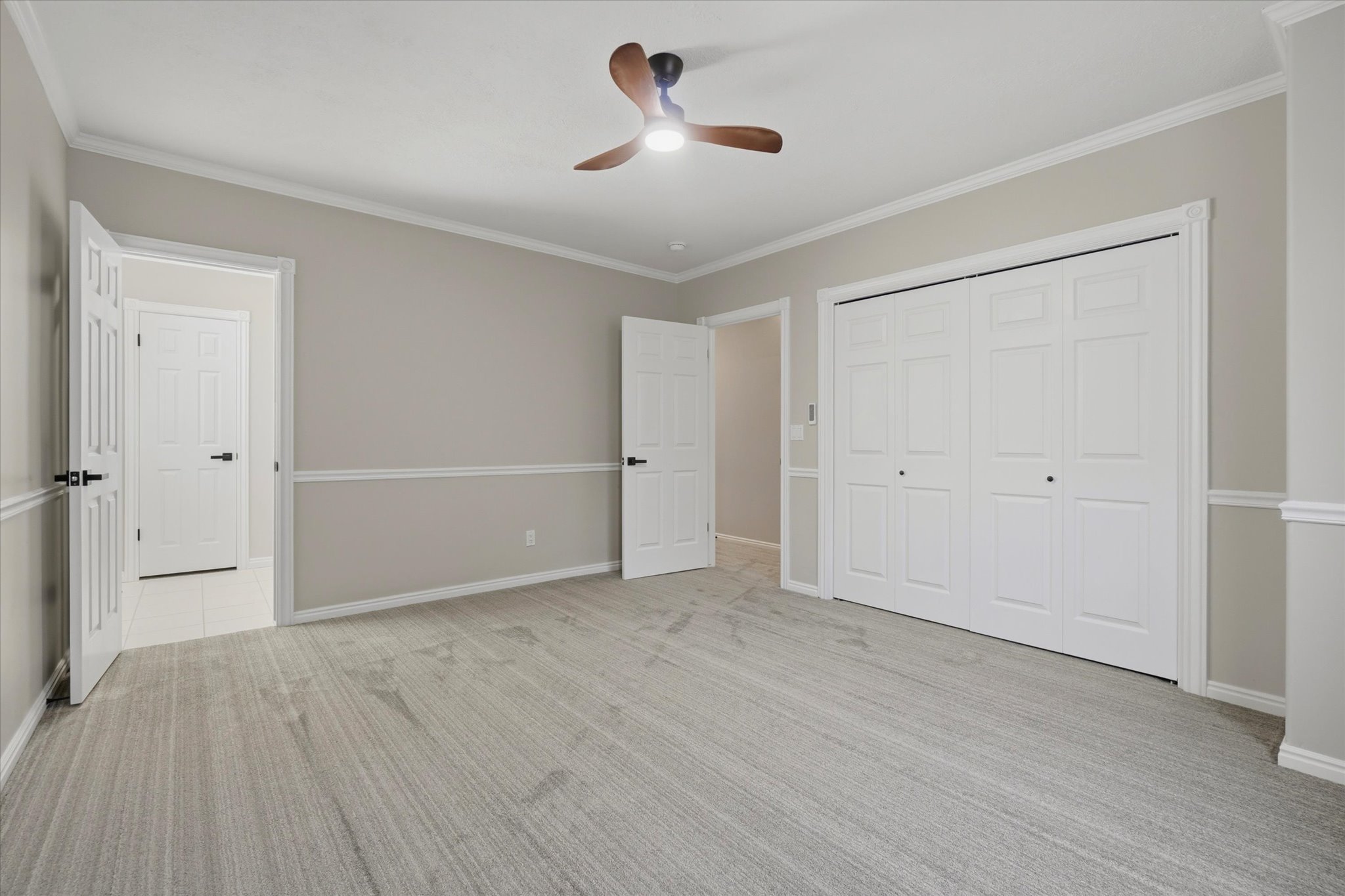 Spacious room featuring light grey wall paint, white trim, and crown molding