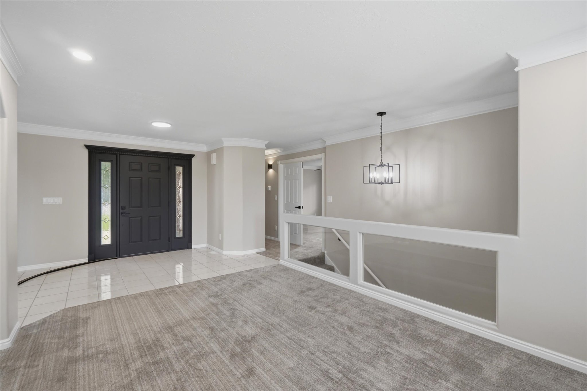 Entry foyer with a black paneled door, decorative glass sidelights, and white tile flooring