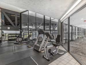Fitness center featuring a concrete ceiling, full-height windows, a selection of exercise equipment, and dedicated rubber flooring