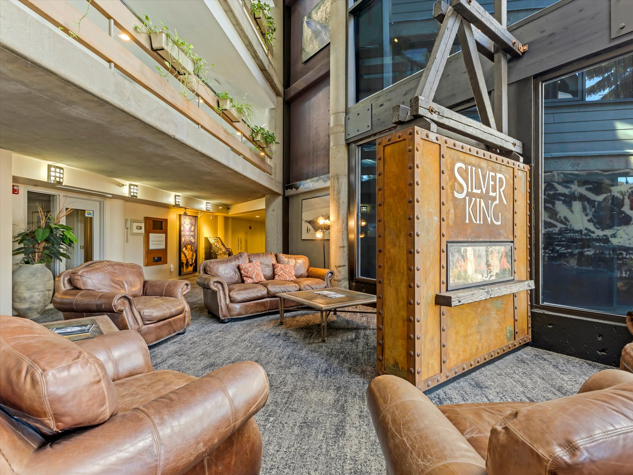 Spacious common area featuring an industrial-inspired design element, tall windows, multi-level balconies with planters, and recessed lighting