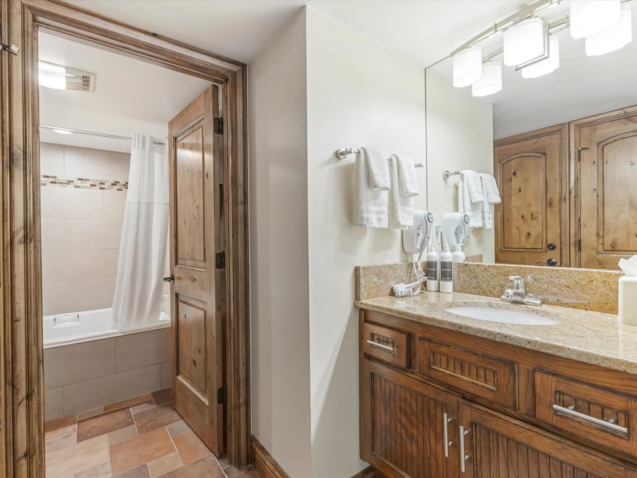 Bathroom featuring a wood-finish vanity with a stone countertop and an undermount sink
