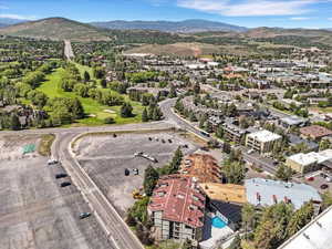 Mountainous landscape featuring a golf course, expansive parking areas, and mixed-use buildings