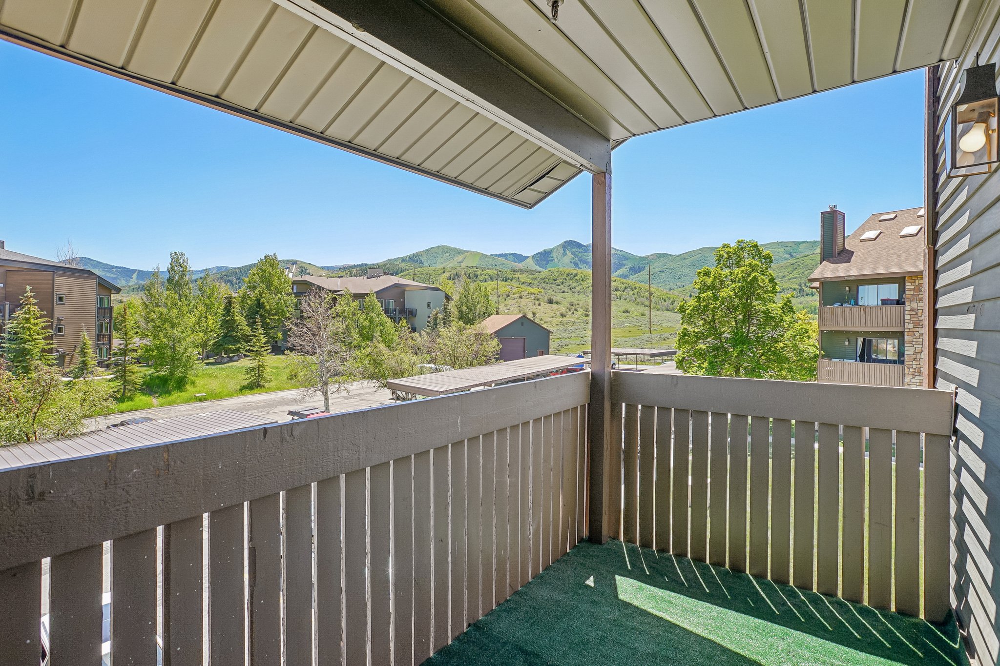 Private balcony with artificial turf flooring, offering a mountain backdrop and surrounding greenery