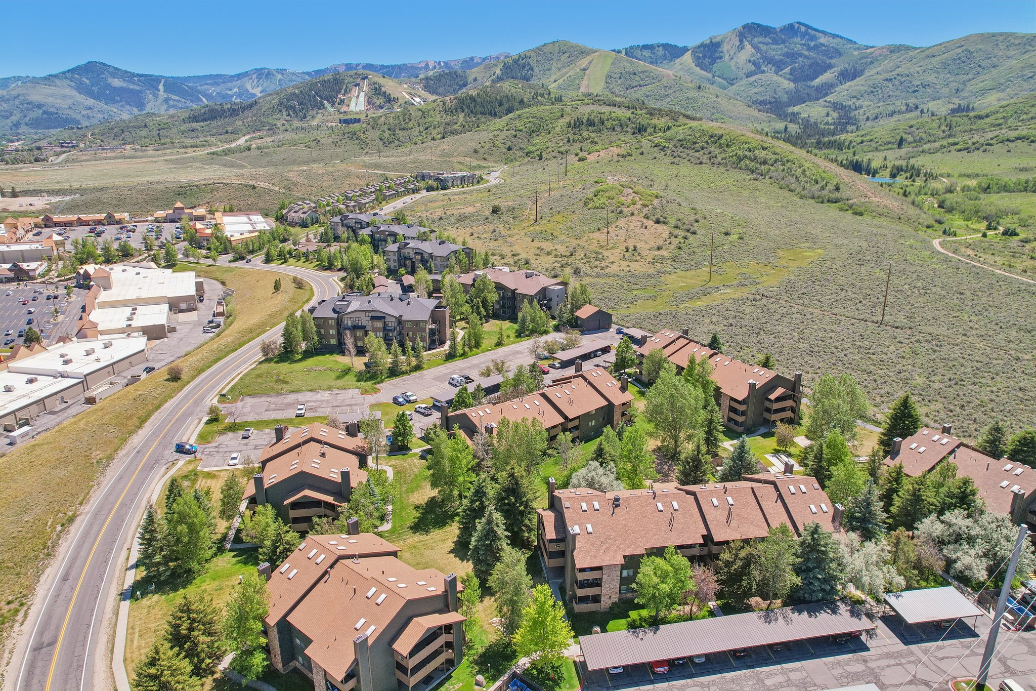 Aerial perspective showcasing multiple residential buildings with brown shingle roofs, surrounded by mature trees