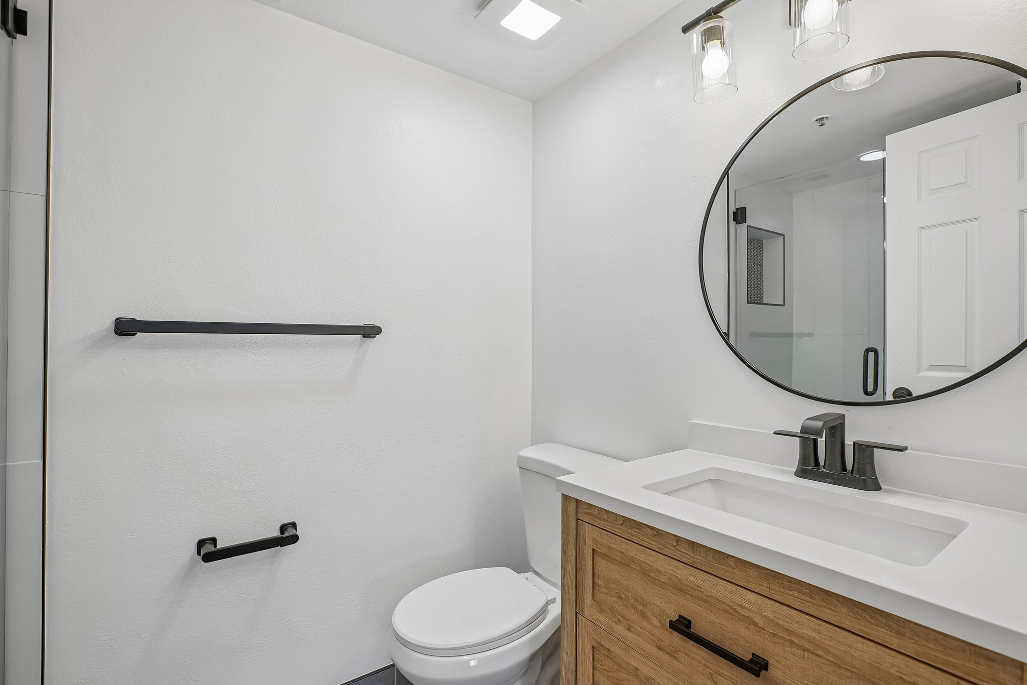 Modern bathroom featuring a wood-finish vanity with a white countertop and integrated sink